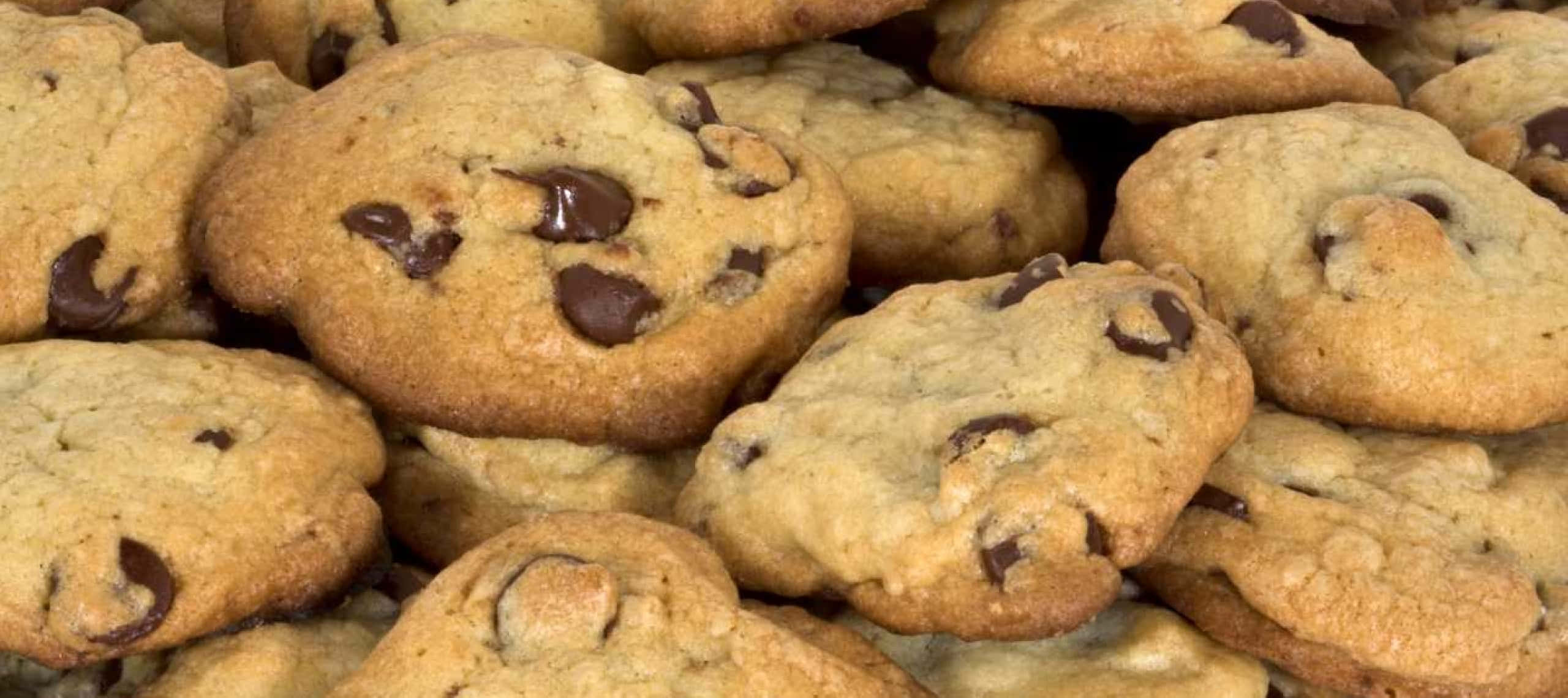 1440p Cookies 桌布 壁紙 — 新鮮出爐的巧克力餅乾特寫，堆疊在一起，邊緣呈金黃色，並有融化的巧克力塊。