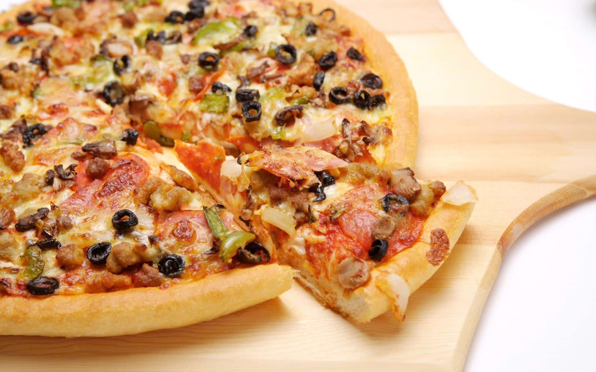 Pizza 桌布 壁紙 — 新鮮出爐的披薩，上面有義大利辣香腸、橄欖和青椒，放在木板上，其中一片被拿起。