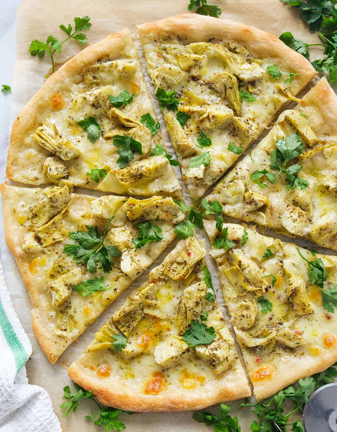 Pizza 桌布 壁紙 — 新鮮出爐的朝鮮薊披薩切成楔形，並用歐芹裝飾在烘焙紙上。