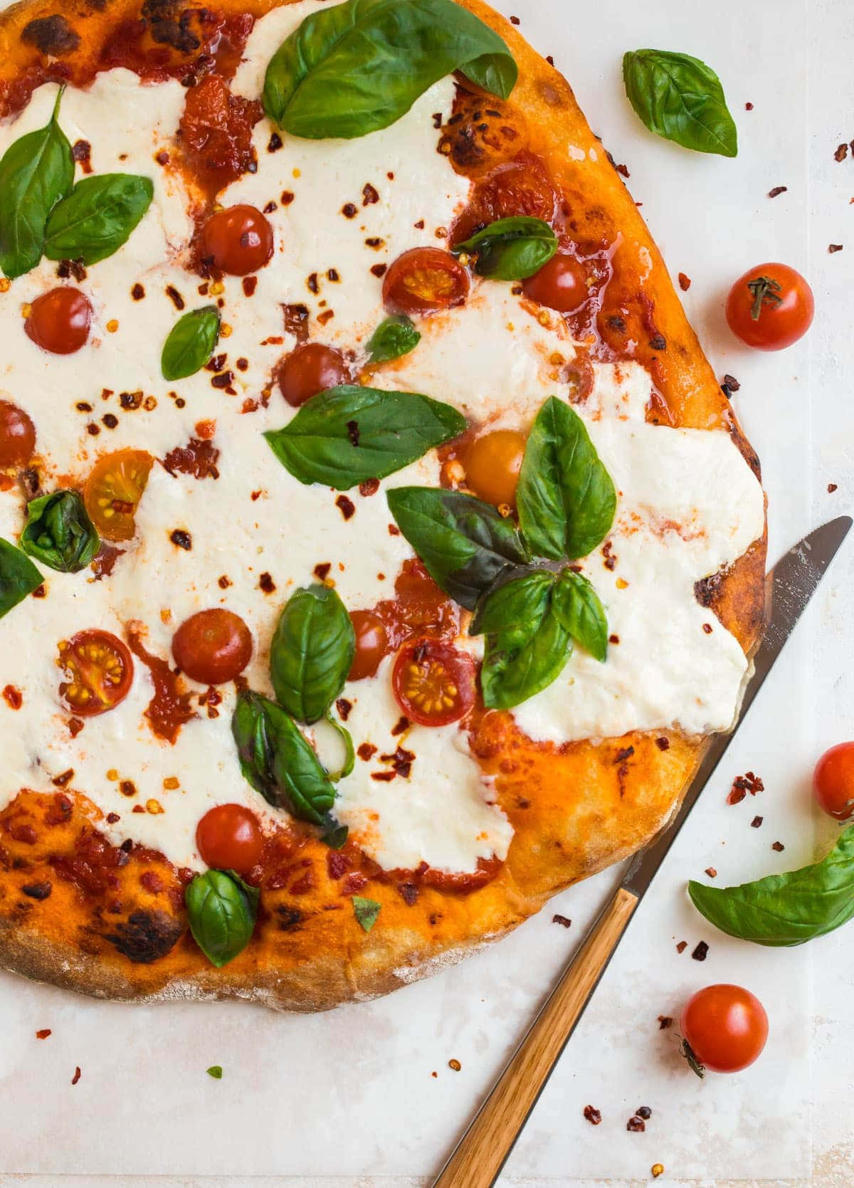 Pizza 桌布 壁紙 — 新鮮出爐的瑪格麗特披薩，上面鋪有融化的莫扎瑞拉起司、櫻桃番茄和羅勒葉，放在白色表面上。