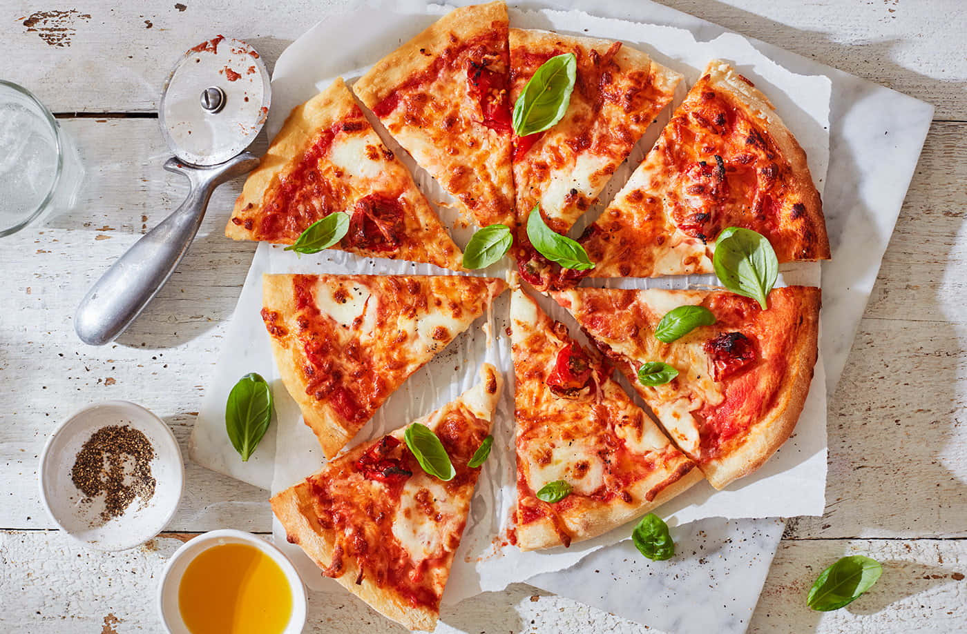 Pizza 桌布 壁紙 — 新鮮出爐的瑪格麗特披薩，切片並用羅勒葉裝飾，放在質樸的白色木桌上。