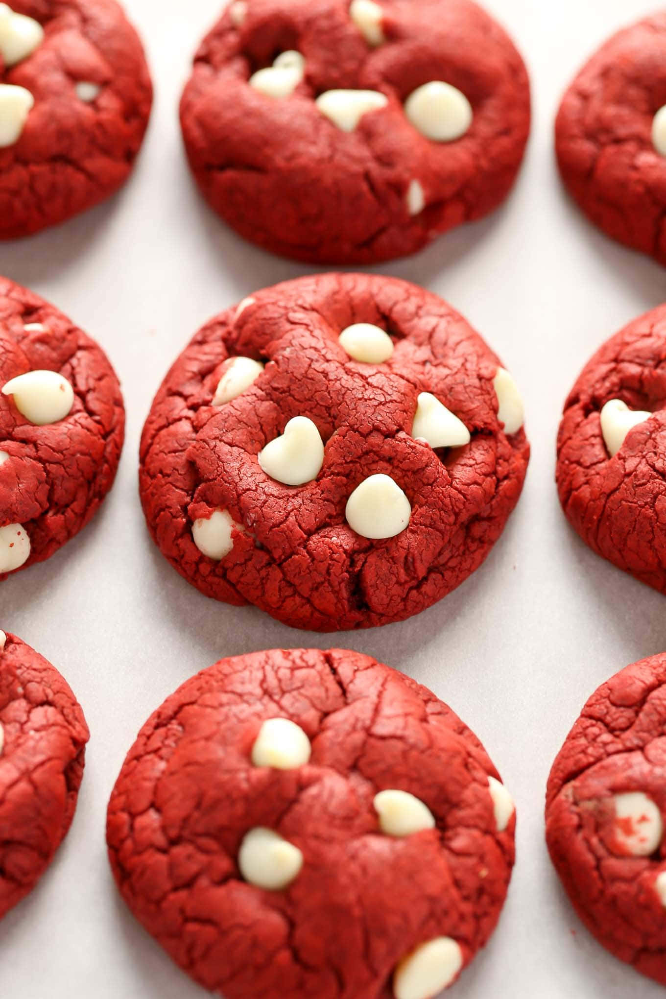 Cookie 桌布 壁紙 — 新鮮出爐的紅絲絨餅乾，搭配白巧克力碎片，整齊擺放在白色烘焙紙上。