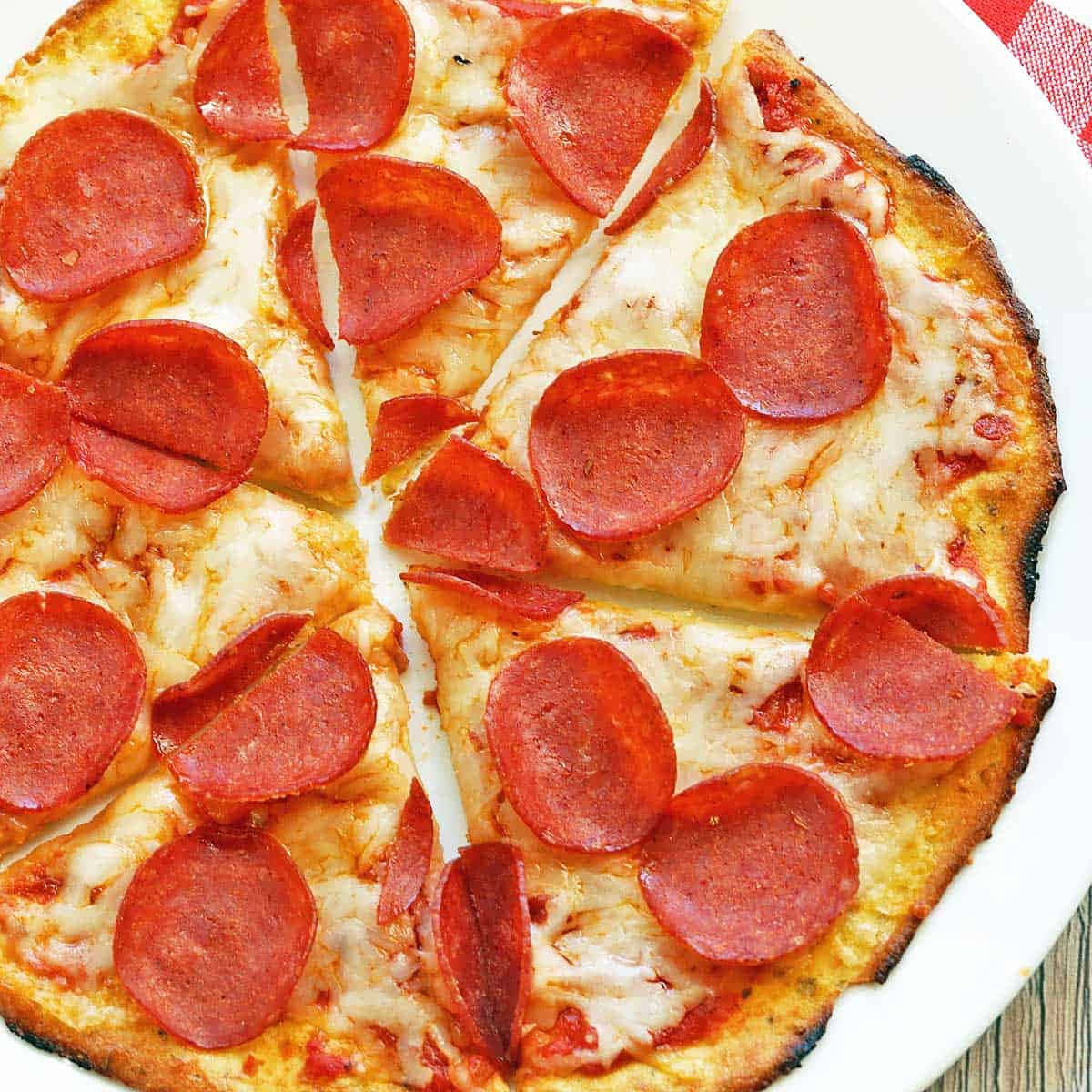 Pizza 桌布 壁紙 — 新鮮出爐的義大利辣味香腸披薩，融化的起司和酥脆的餅皮，切片放在白色盤子上。