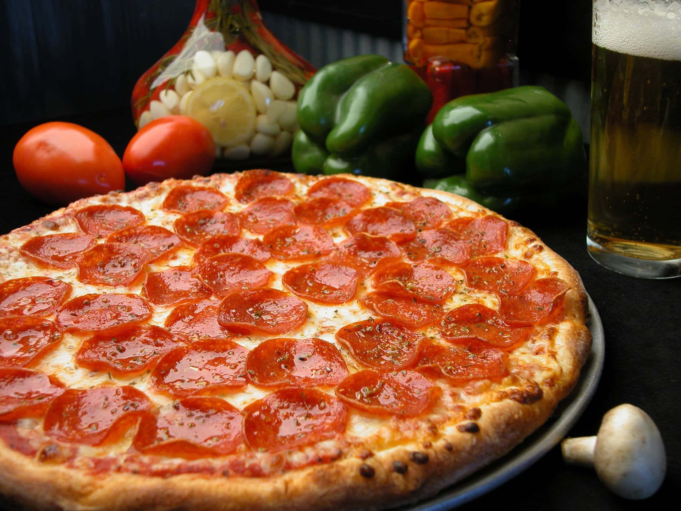Pizza 桌布 壁紙 — 新鮮出爐的義大利辣香腸披薩，配上融化的起司和香草，放在托盤上，周圍有番茄、甜椒和一杯啤酒。