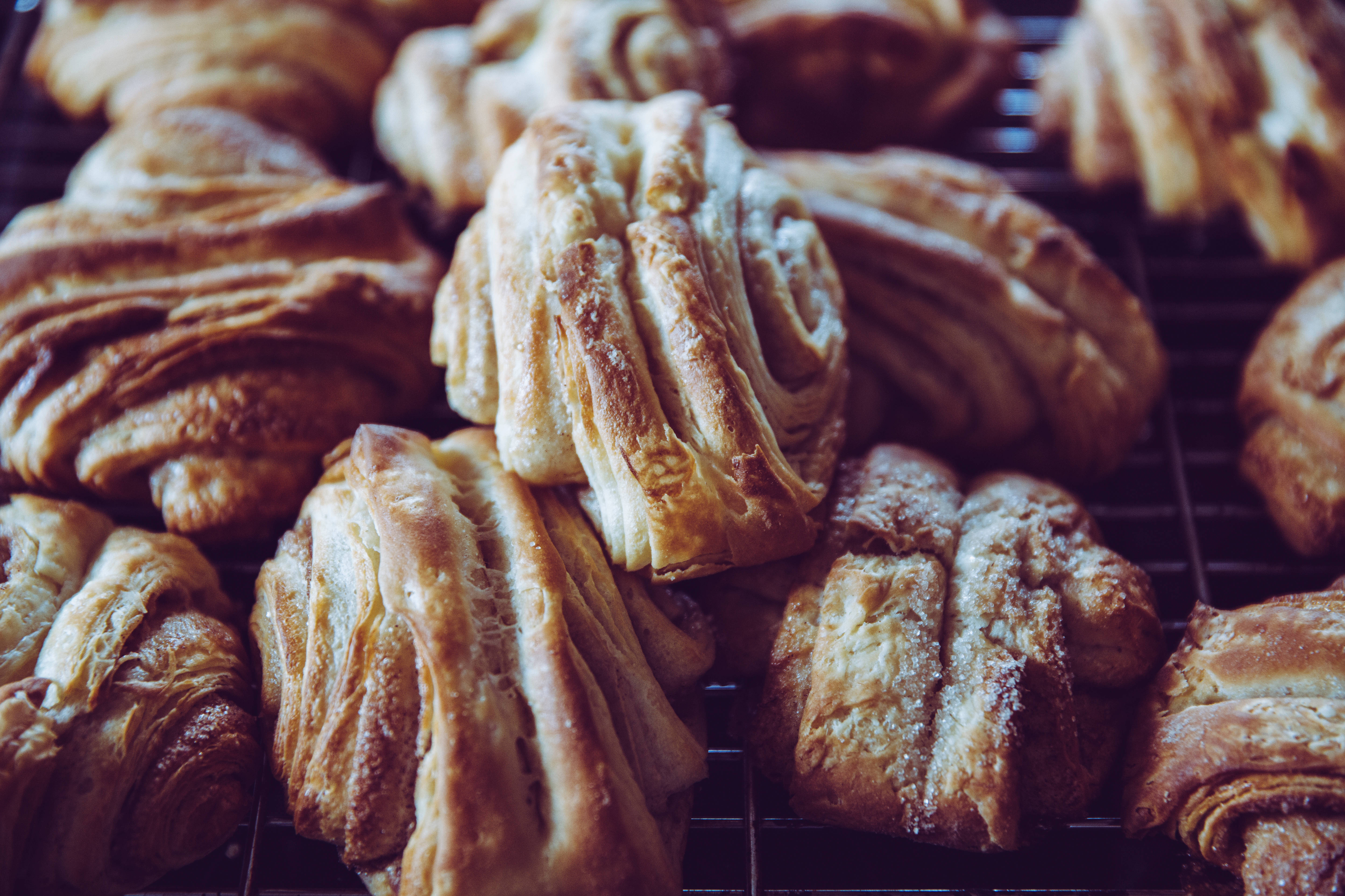 Pastries 桌布 壁紙 — 新鮮出爐的金色可頌，層層酥脆，在深色金屬架上冷卻。