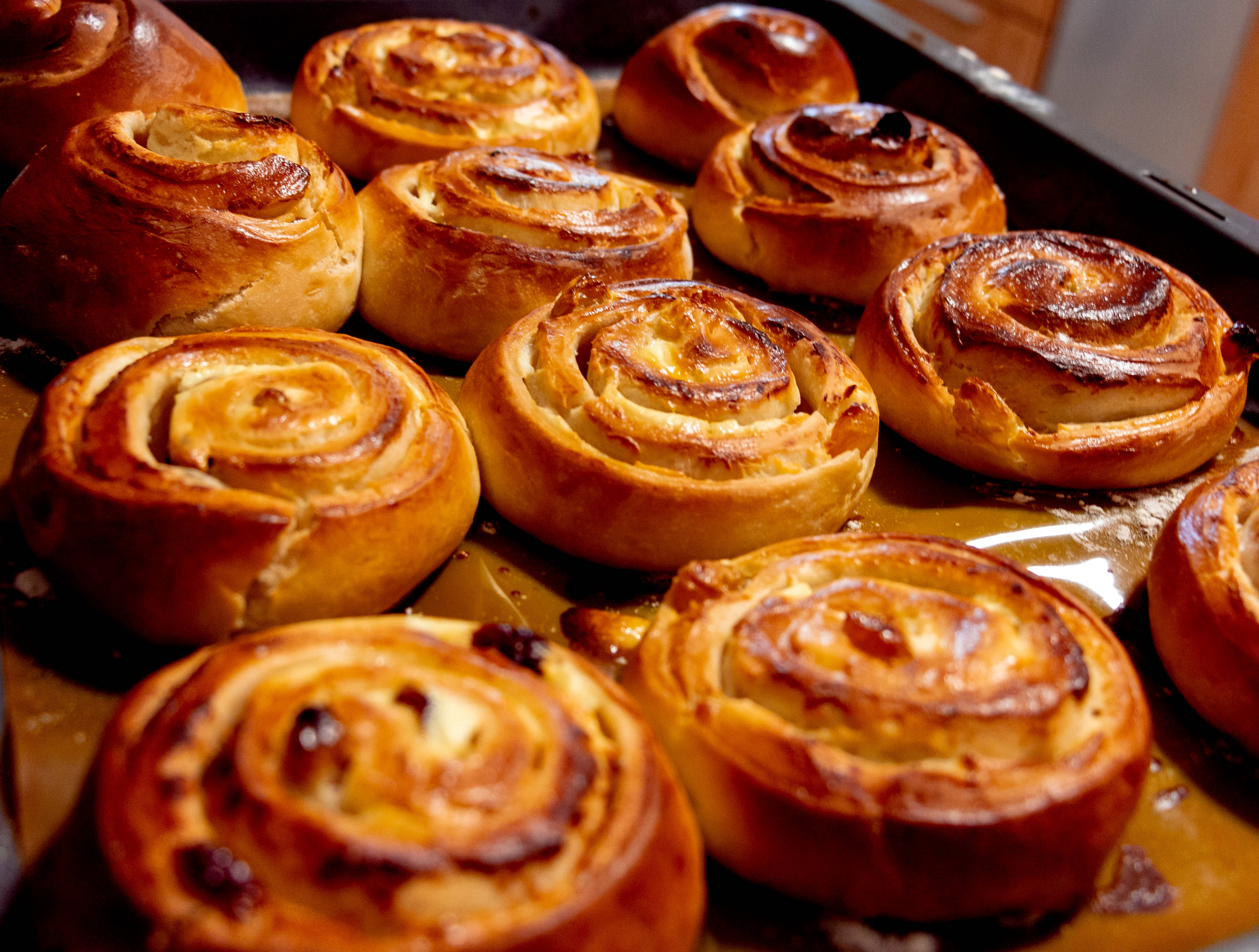 Pastry 桌布 壁紙 — 新鮮出爐的金黃色肉桂捲，在烤盤上閃耀著糖和葡萄乾。