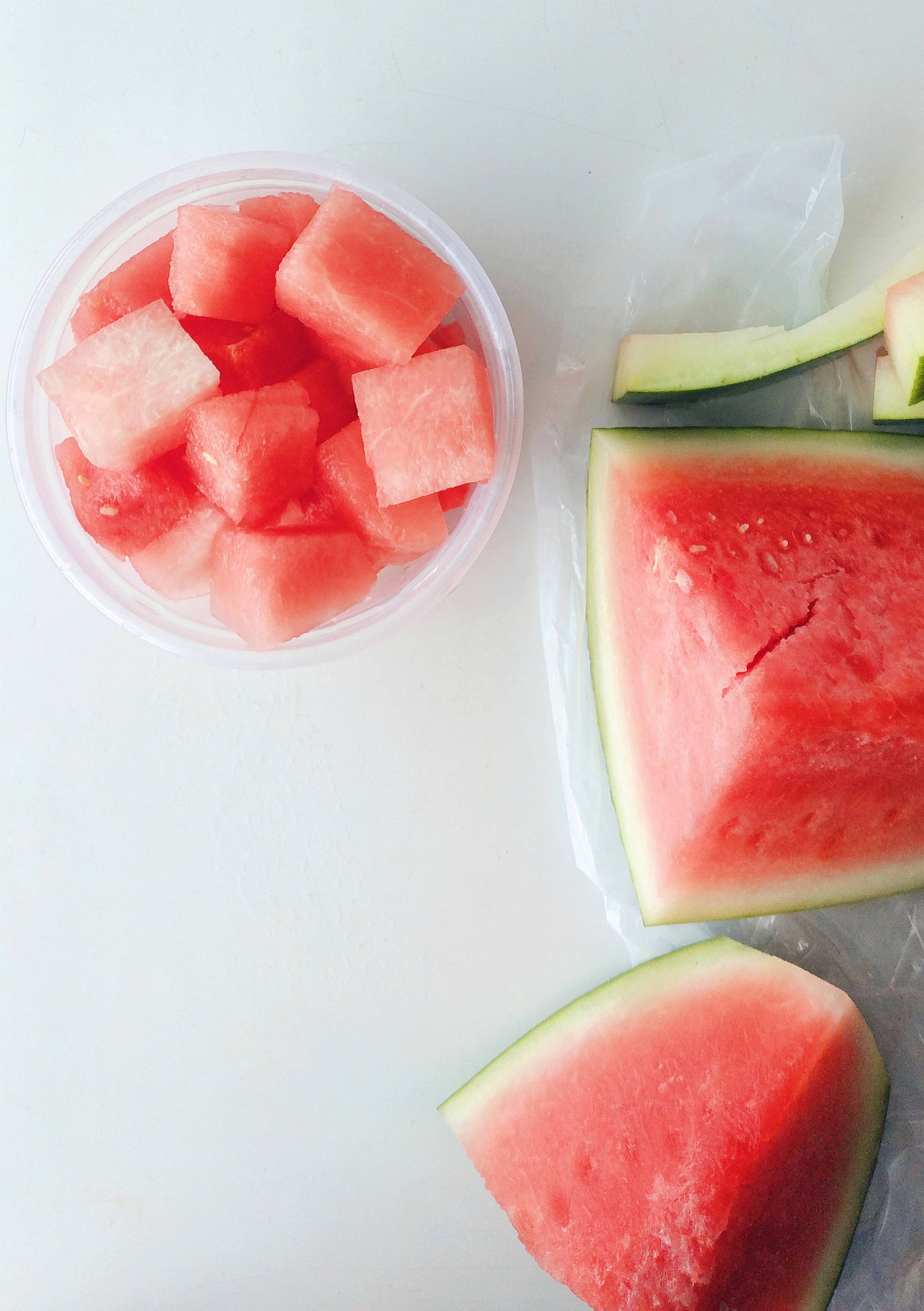 Watermelon 桌布 壁紙 — 新鮮切好的西瓜片和方塊排列在乾淨的白色表面上，呈現簡約美學。