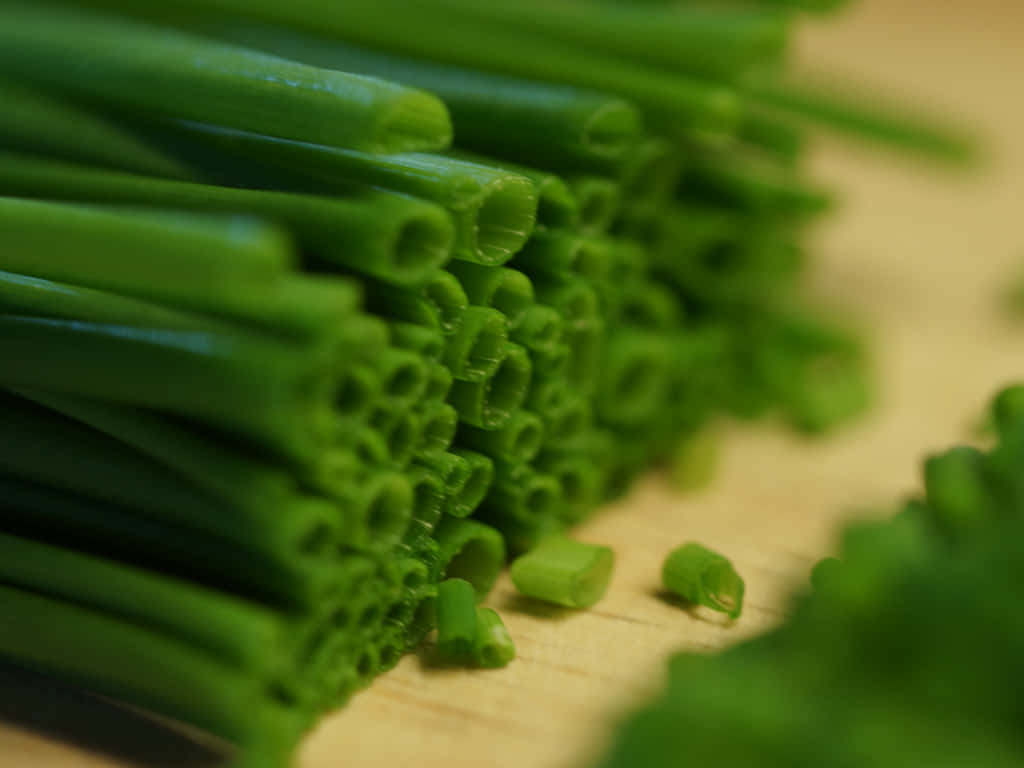 Food Photography 桌布 壁紙 — 新鮮切好的青蔥排列成充滿活力的綠色堆，放在溫暖的木砧板上。