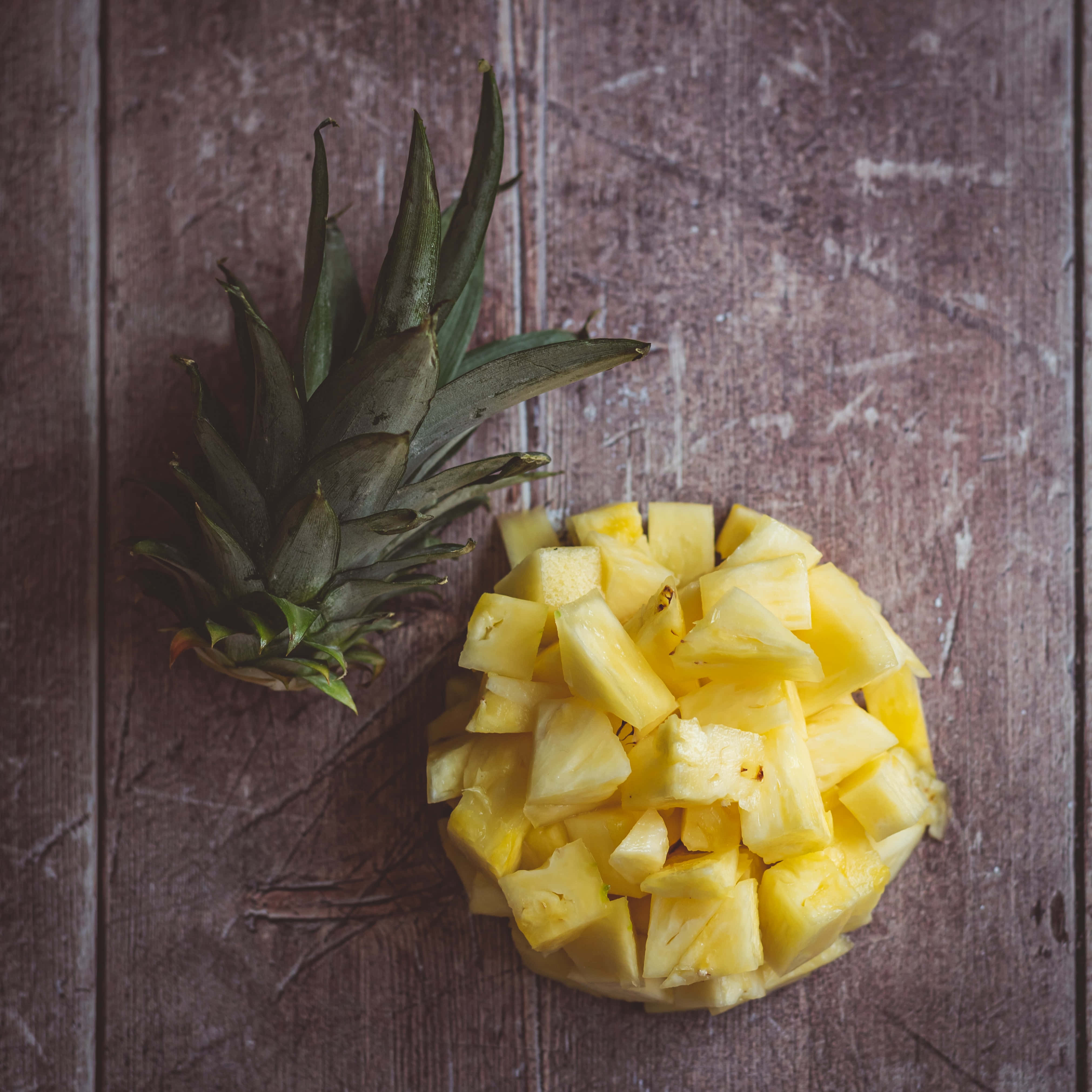 Pineapple 桌布 壁紙 — 新鮮切好的鳳梨塊和鳳梨冠放在質樸風化的木質表面上。