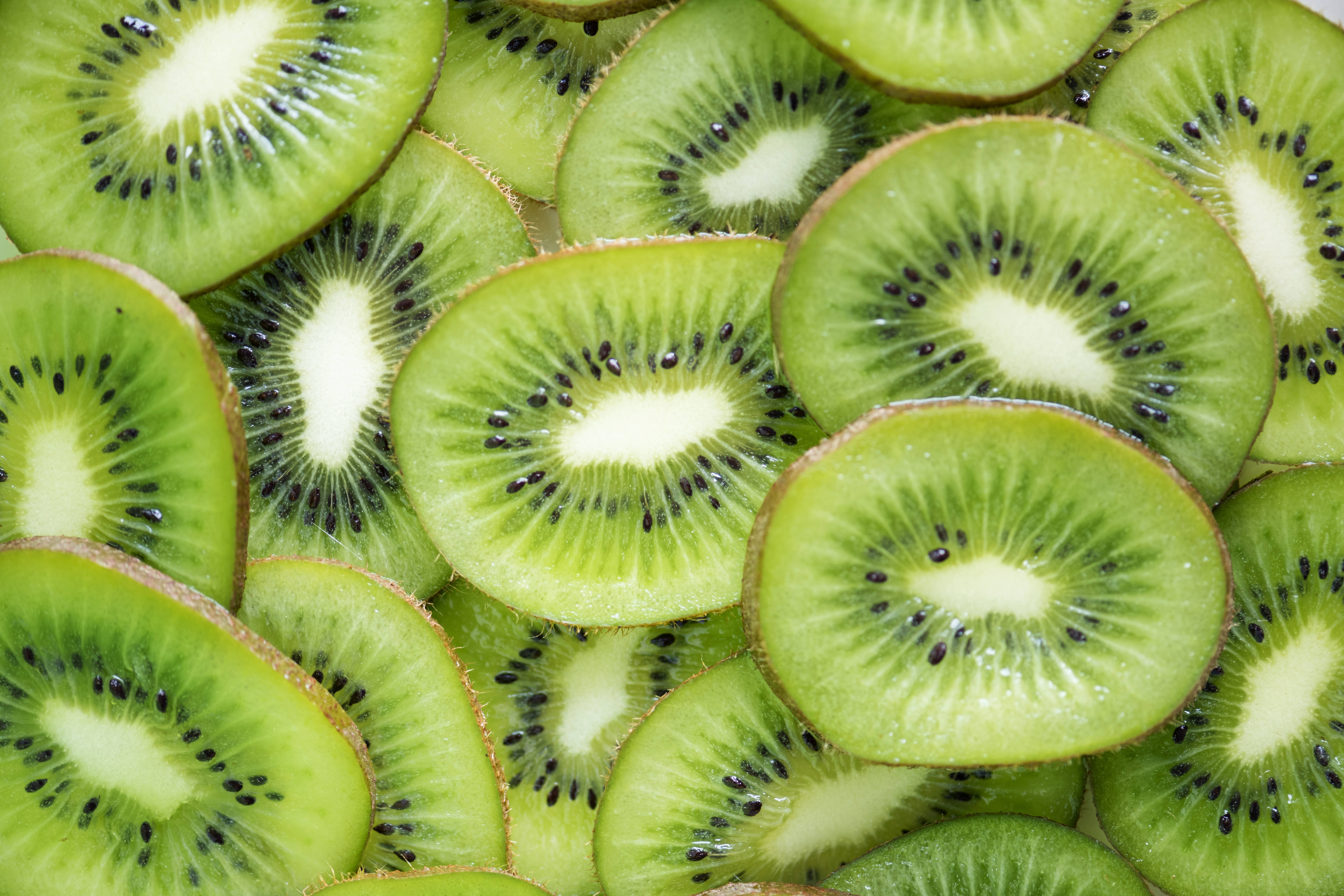 Kiwi 桌布 壁紙 — 新鮮切片奇異果的鮮豔特寫，展現多汁的綠色果肉和黑色種子。