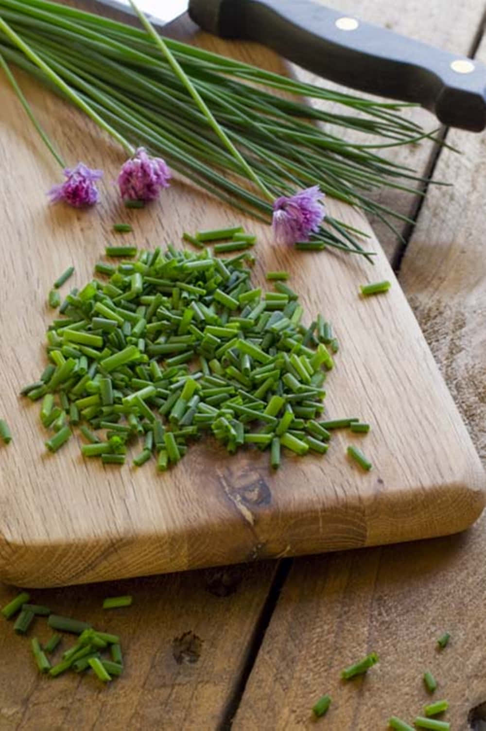 Food Photography 桌布 壁紙 — 新鮮切碎的細香蔥帶有紫色花朵，放在一把刀旁邊的鄉村風格木製砧板上。
