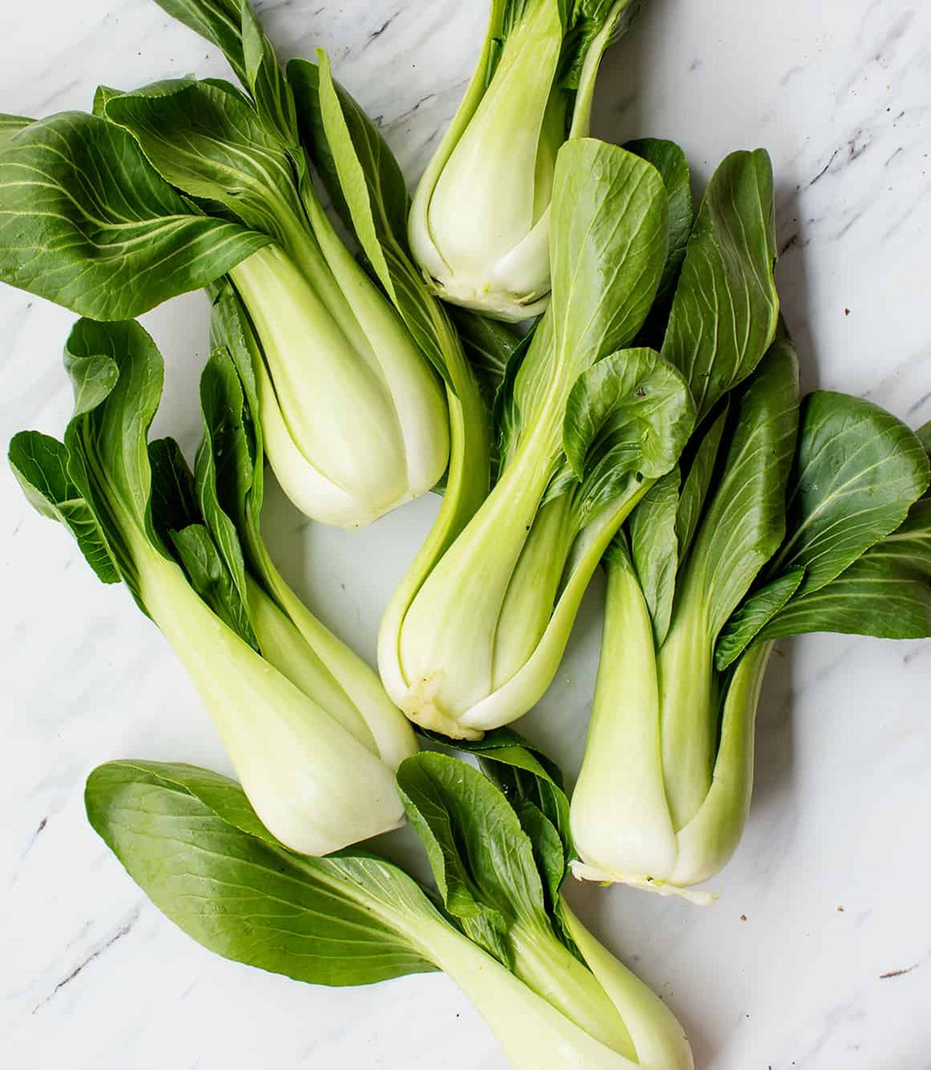 Vegetables 桌布 壁紙 — 新鮮小白菜，翠綠葉片及淺色莖部，整齊排列在白色大理石表面上。
