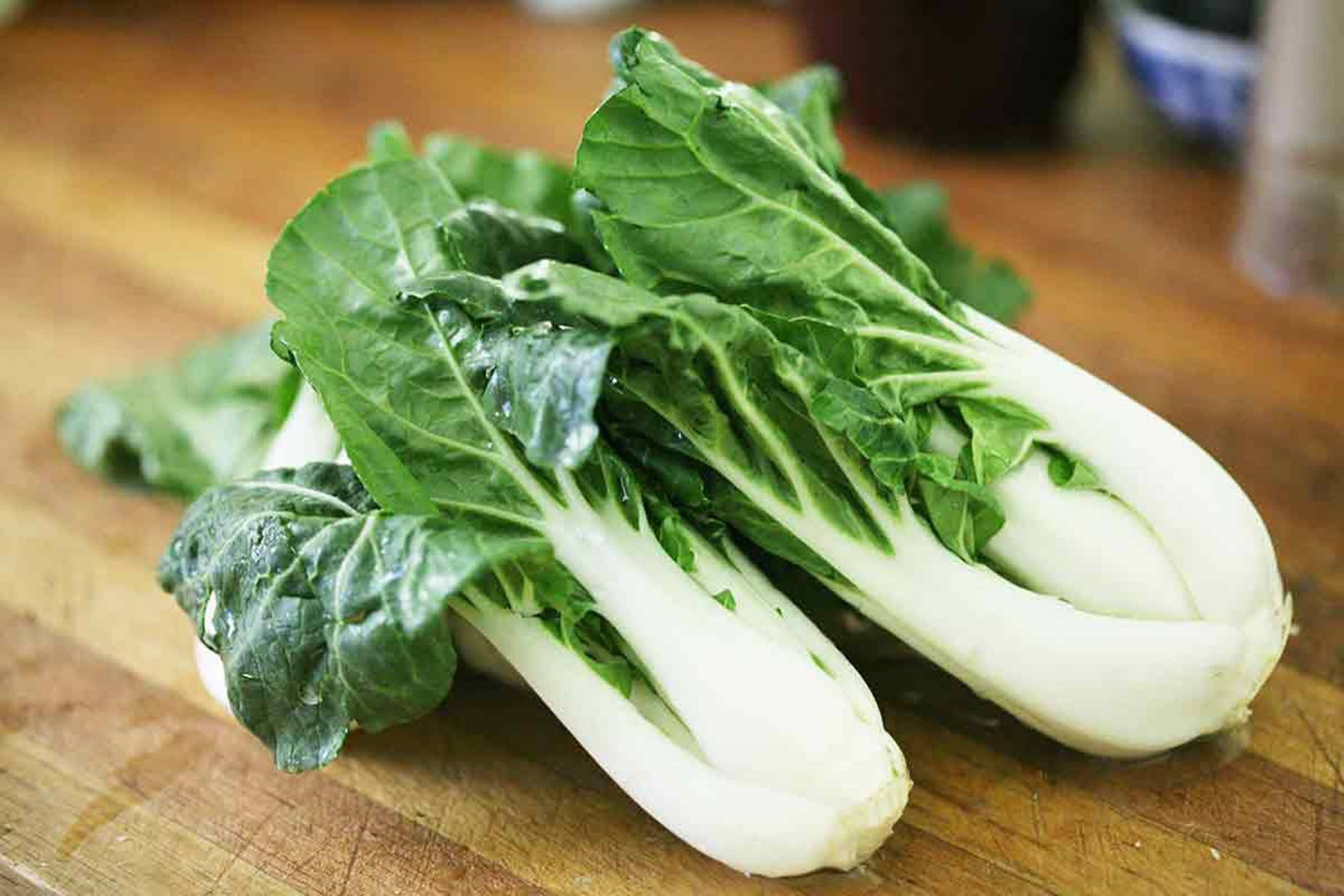 Vegetables 桌布 壁紙 — 新鮮小白菜，莖部潔白爽脆，葉片翠綠鮮活，置於木製砧板上。