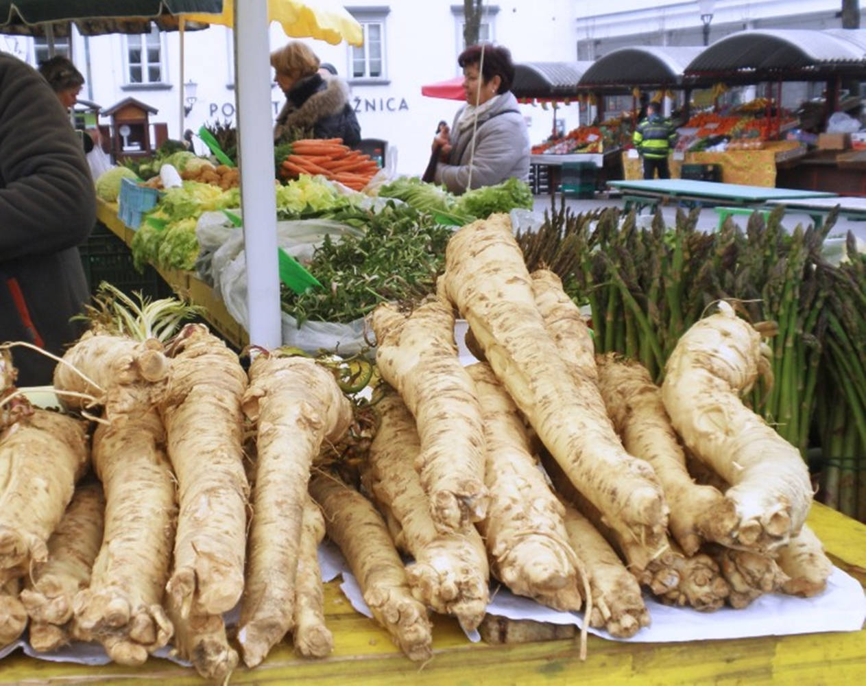 Vegetables 桌布 壁紙 — 新鮮收成的歐洲防風草和蘆筍在熱鬧的戶外農夫市集攤位上展示。