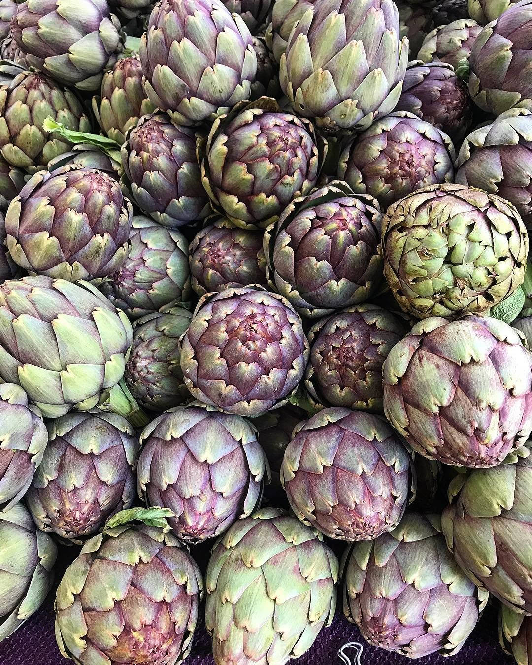Vegetables 桌布 壁紙 — 新鮮朝鮮薊帶有紫色和綠色色調，在市場陳列中堆疊在一起的近距離特寫。