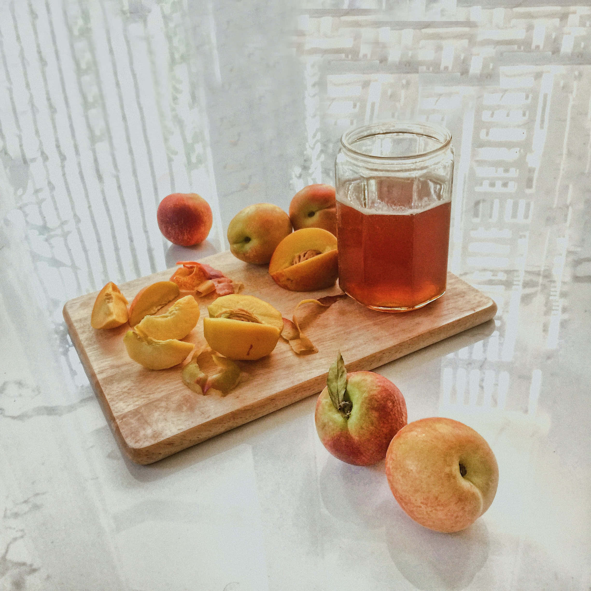 Peaches 桌布 壁紙 — 新鮮桃子切片和整個放在木板上，旁邊有一罐桃子糖漿，放在窗邊的大理石檯面上。