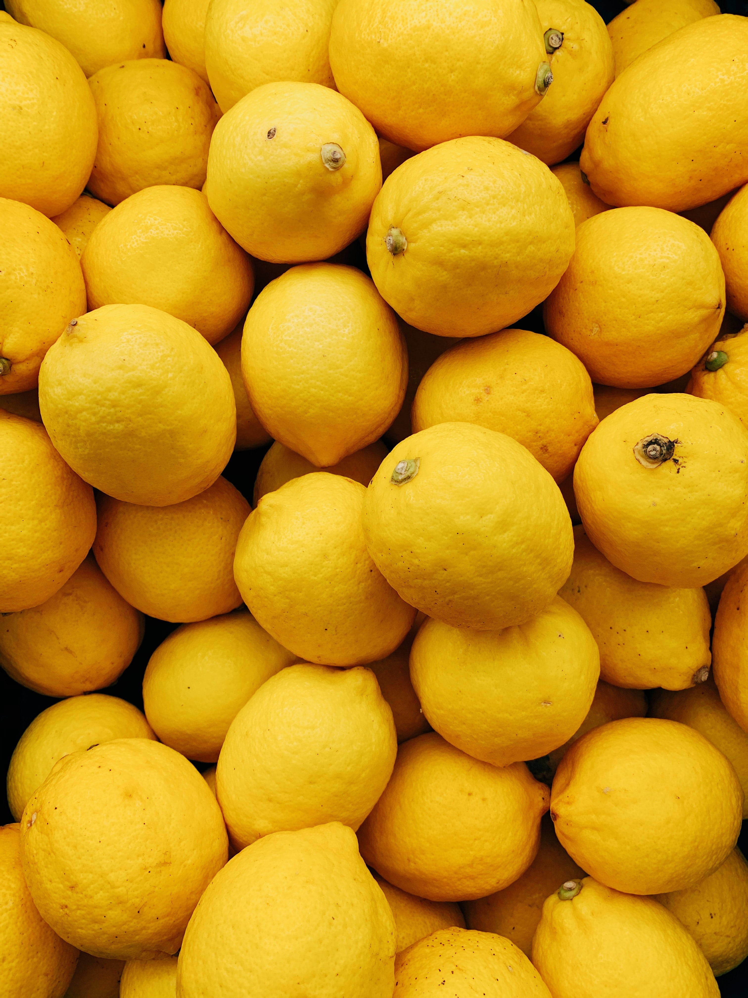 Fruit 桌布 壁紙 — 新鮮檸檬堆疊在一起的鮮豔特寫，展示其紋理黃色外皮和自然瑕疵。