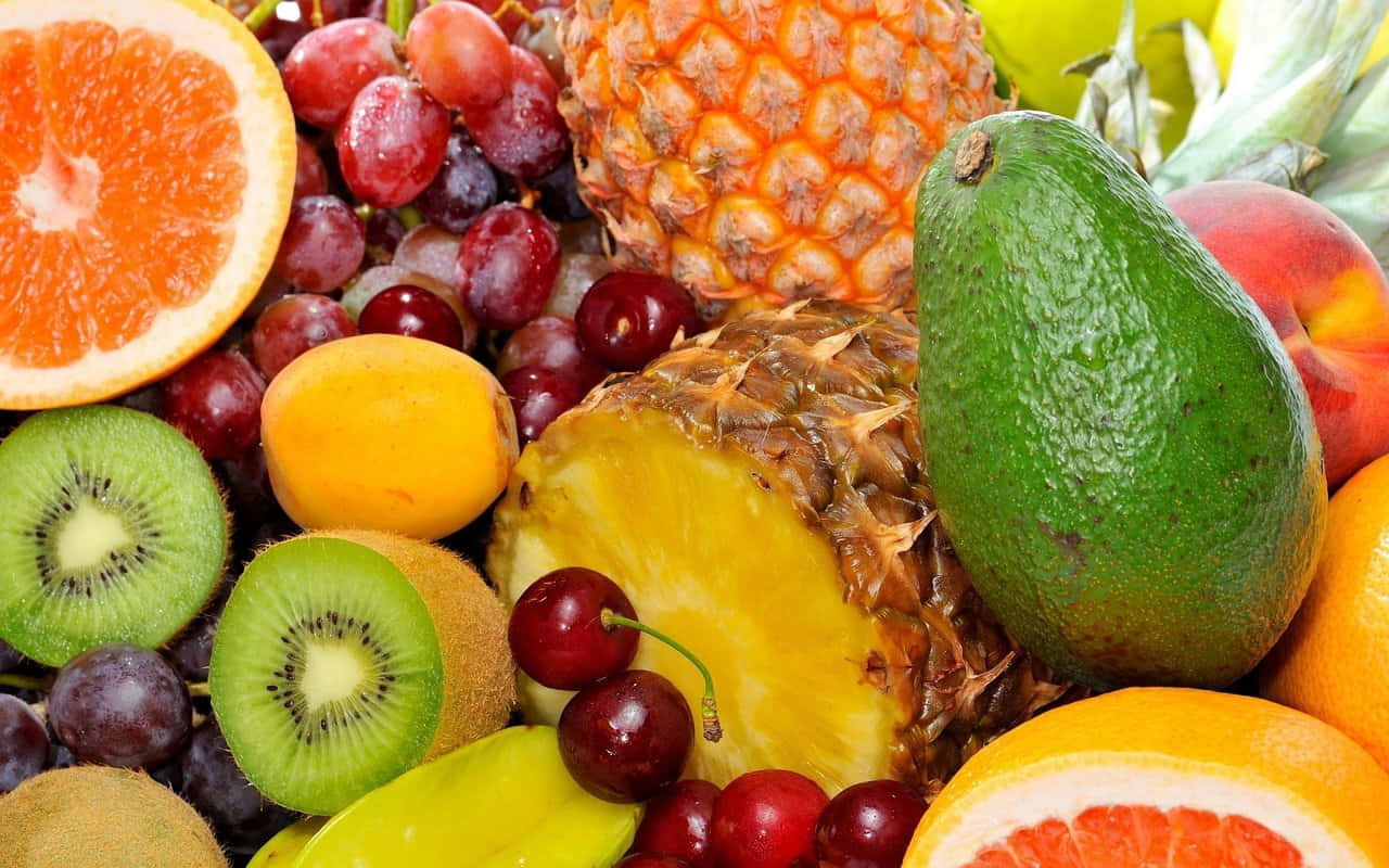 Fruits 桌布 壁紙 — 新鮮水果的特寫，包括鳳梨、酪梨、奇異果和葡萄，色彩和質感豐富。