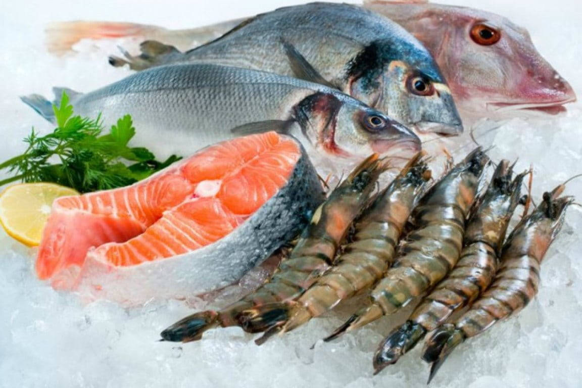 魚 桌布 壁紙 — 新鮮海鮮包括全魚、鮭魚片和蝦，放在碎冰上，以檸檬和歐芹裝飾。