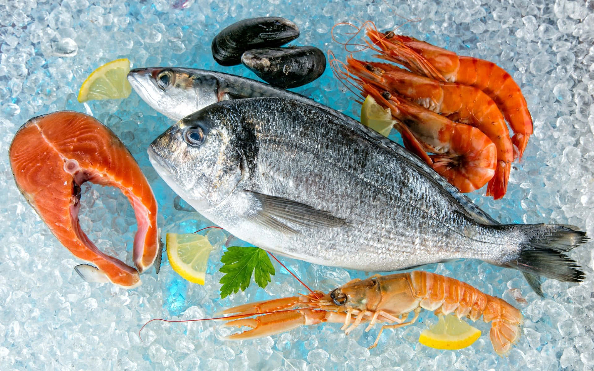 海鮮 桌布 壁紙 — 新鮮海鮮包括鮭魚片、全魚、蝦和貽貝，放在碎冰上，配以檸檬角和歐芹。