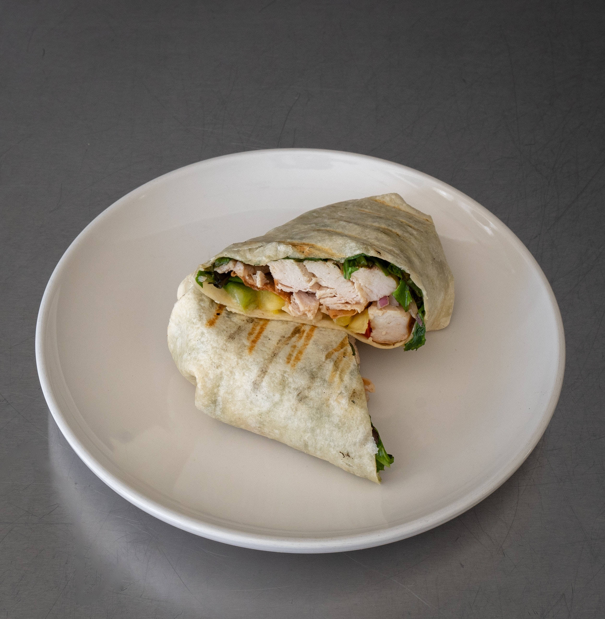 Burrito 桌布 壁紙 — 新鮮烤雞肉捲切成兩半，放在白色盤子上，背景為灰色金屬質感。