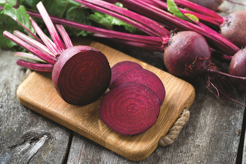 beetroot 桌布 壁紙 — 新鮮甜菜根帶有充滿活力的紫色根部及綠色葉子，放在一個木製砧板上，砧板置於一個經風化的木質表面上。