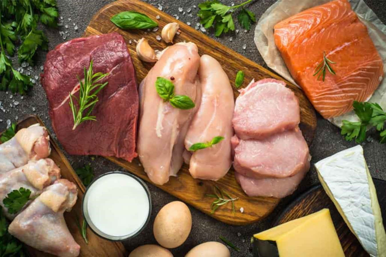 meat 桌布 壁紙 — 新鮮生肉、家禽、魚、乳製品和雞蛋，配上香草和鹽，藝術地擺放在木板上。