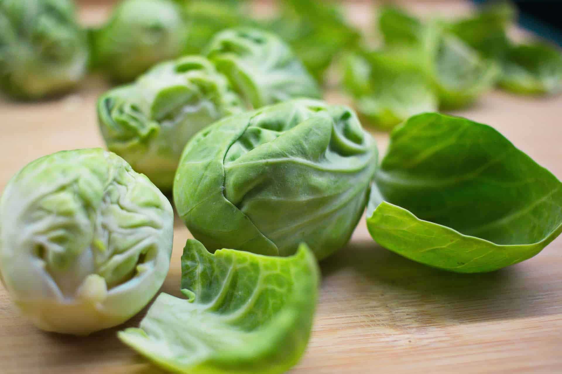 Brussel Sprout 桌布 壁紙 — 新鮮的抱子甘藍，帶有脆綠的葉子，放在溫暖的木砧板上。