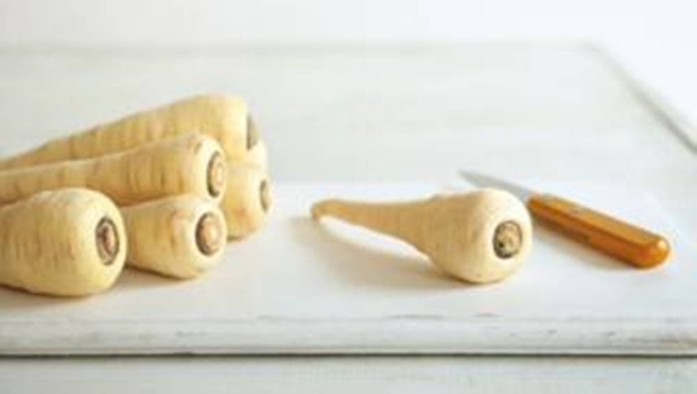 Parsnip 桌布 壁紙 — 新鮮的淡黃色歐洲防風草排列在白色砧板上，旁邊有一把小刀。