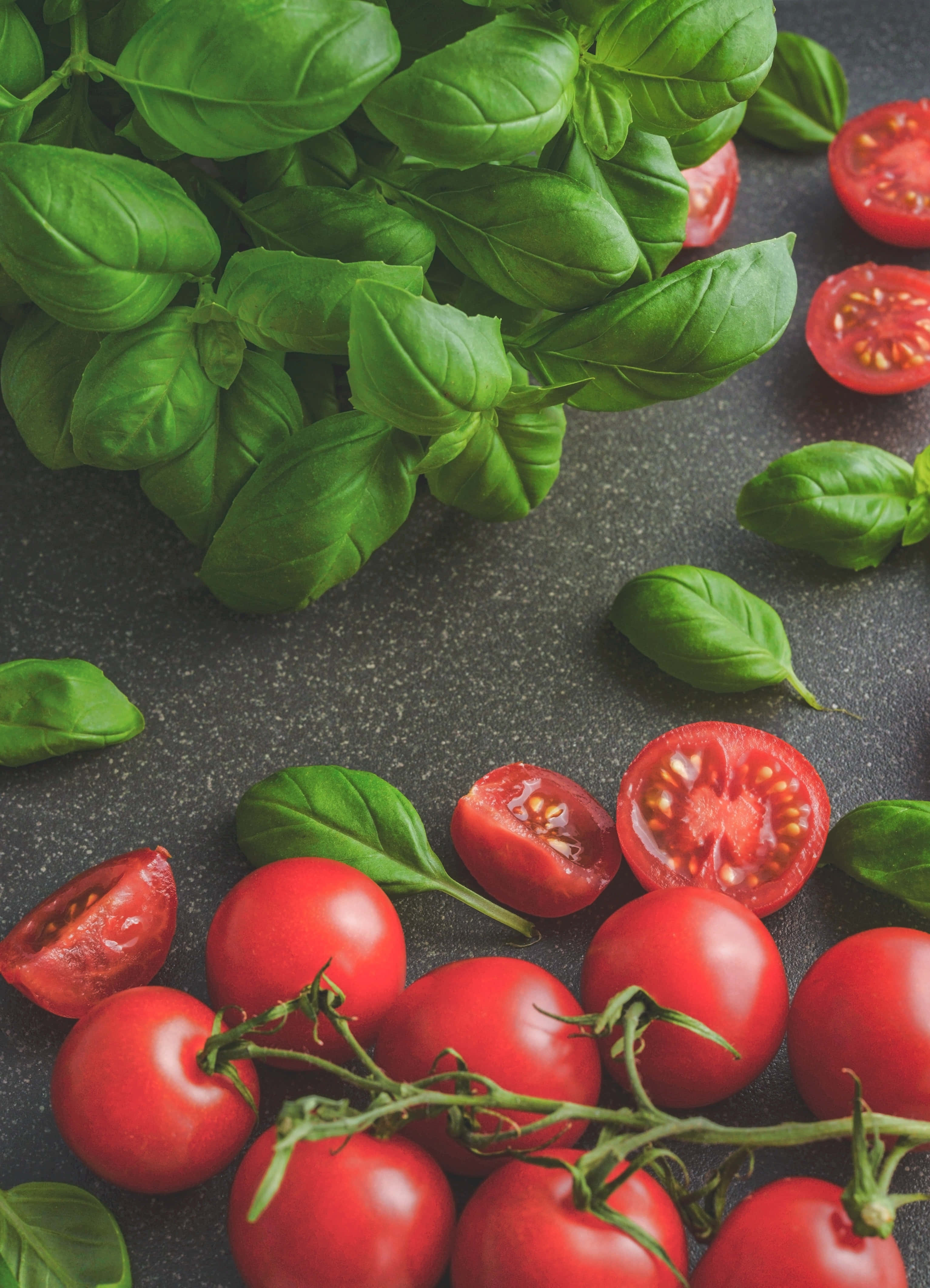 tomato 桌布 壁紙 — 新鮮的紅色櫻桃番茄和充滿活力的綠色羅勒葉排列在深色紋理表面上。