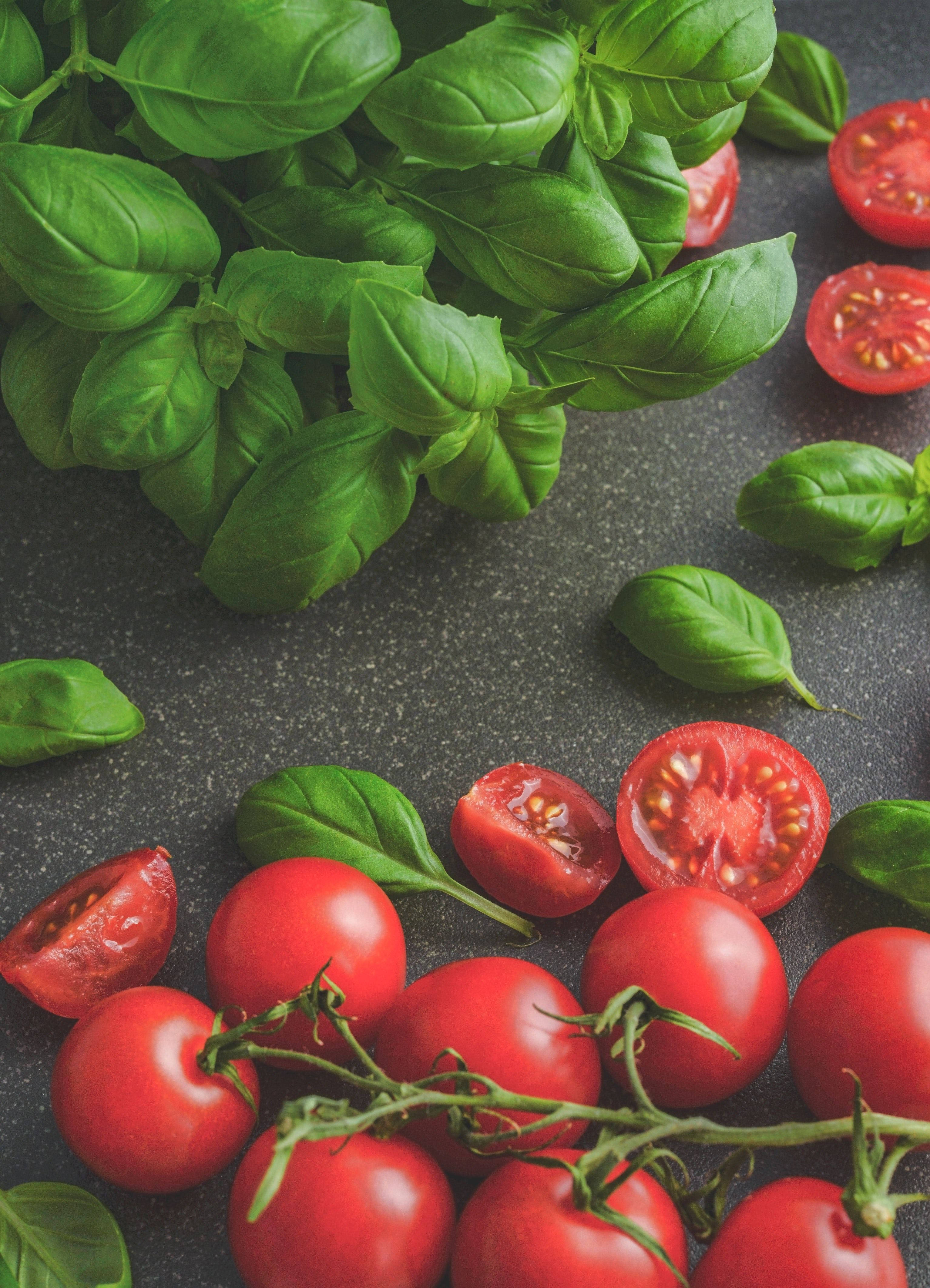 tomato 桌布 壁紙 — 新鮮的紅色櫻桃番茄和充滿活力的綠色羅勒葉排列在深色紋理表面上。