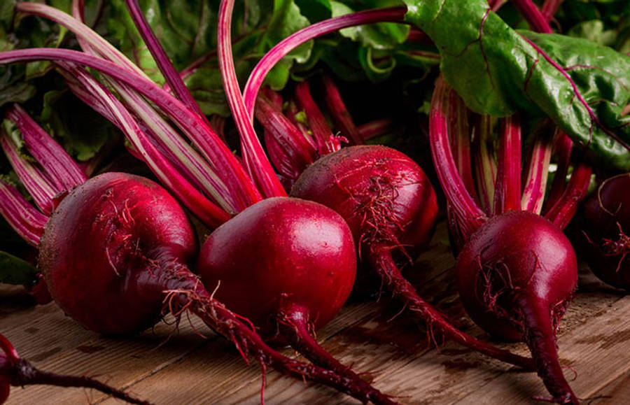 beetroot 桌布 壁紙 — 新鮮的紅色甜菜頭配綠葉，放在質樸的木質表面上。