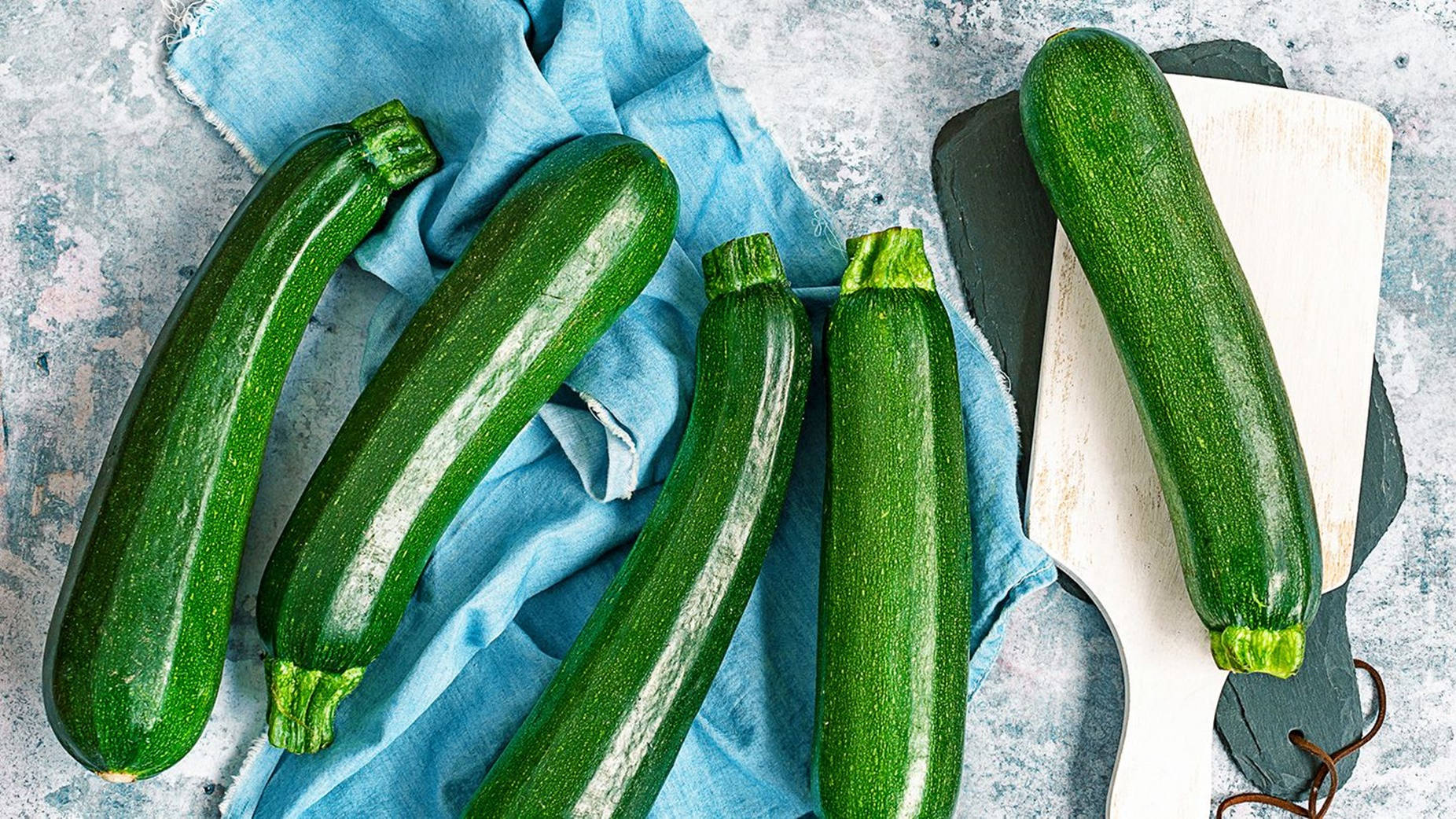 Vegetables 桌布 壁紙 — 新鮮的綠色櫛瓜放在藍色布和木板上，背景為紋理灰色表面。