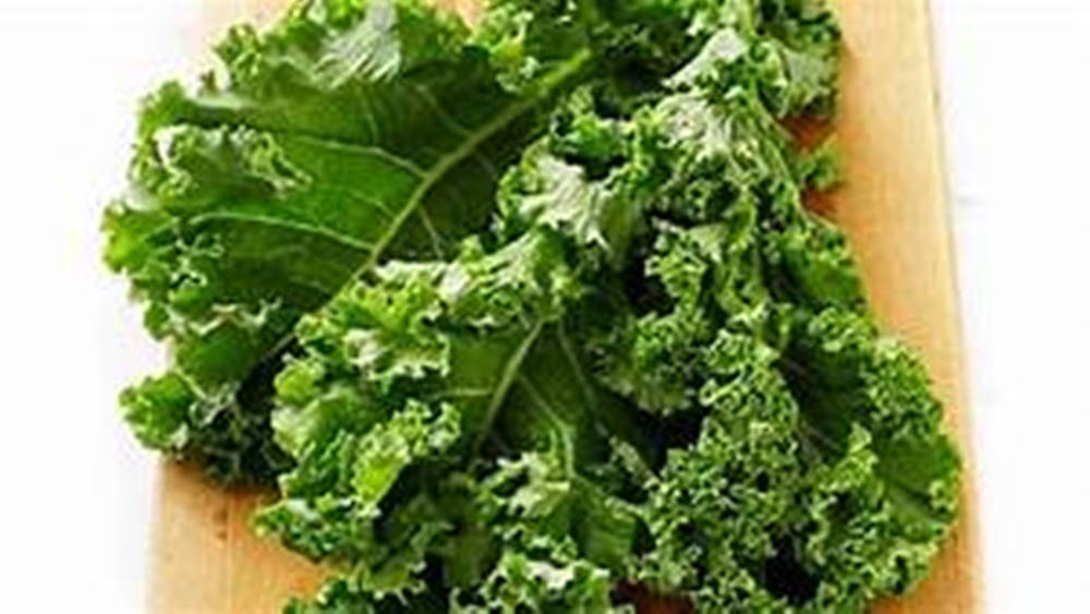 Cabbage 桌布 壁紙 — 新鮮的羽衣甘藍葉，帶有充滿活力的綠色皺褶邊緣，放在淺色木砧板上。