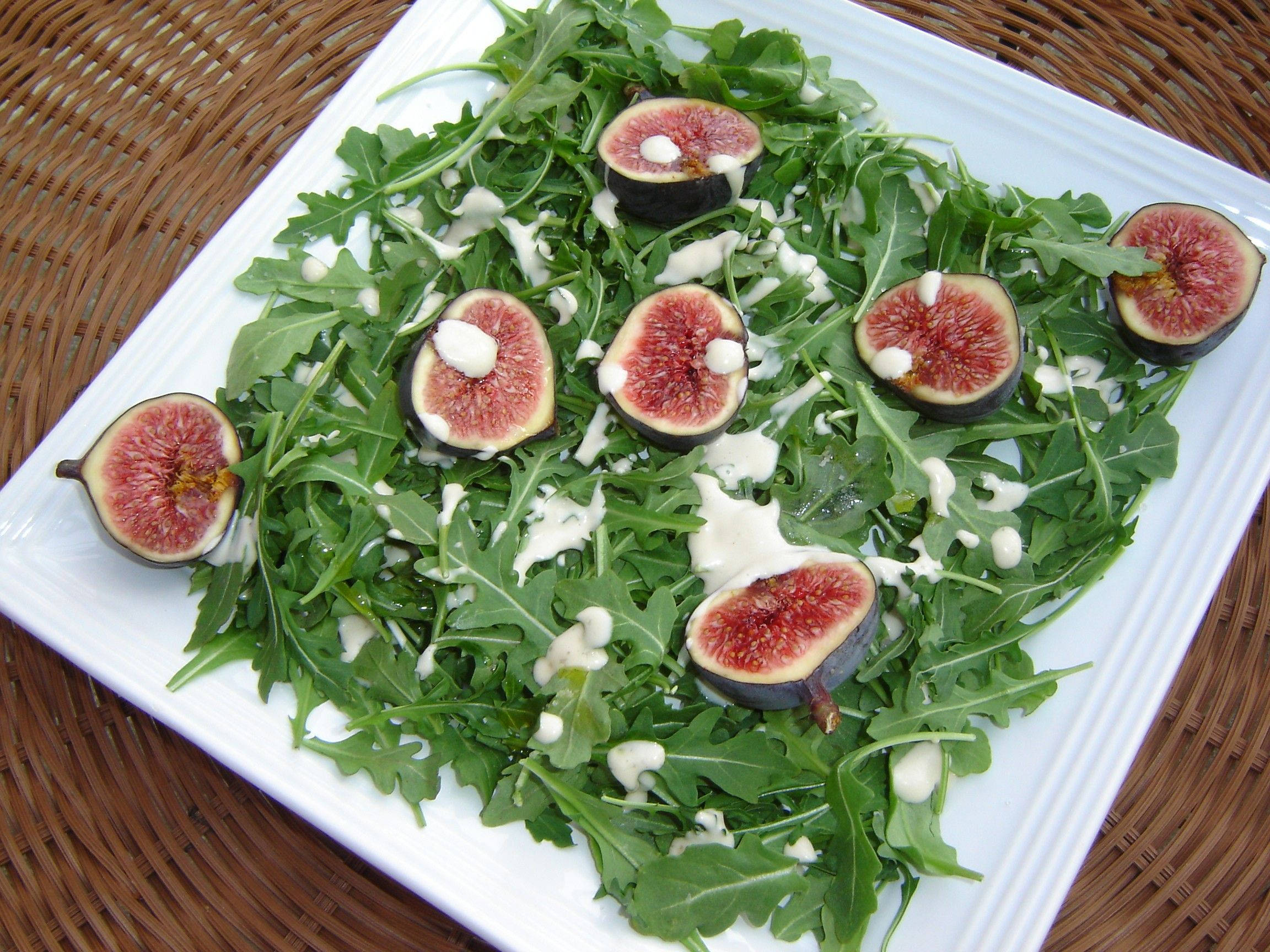 Arugula 桌布 壁紙 — 新鮮的芝麻葉沙拉，上面放有切片無花果和奶油醬汁，盛載於白色盤子上。
