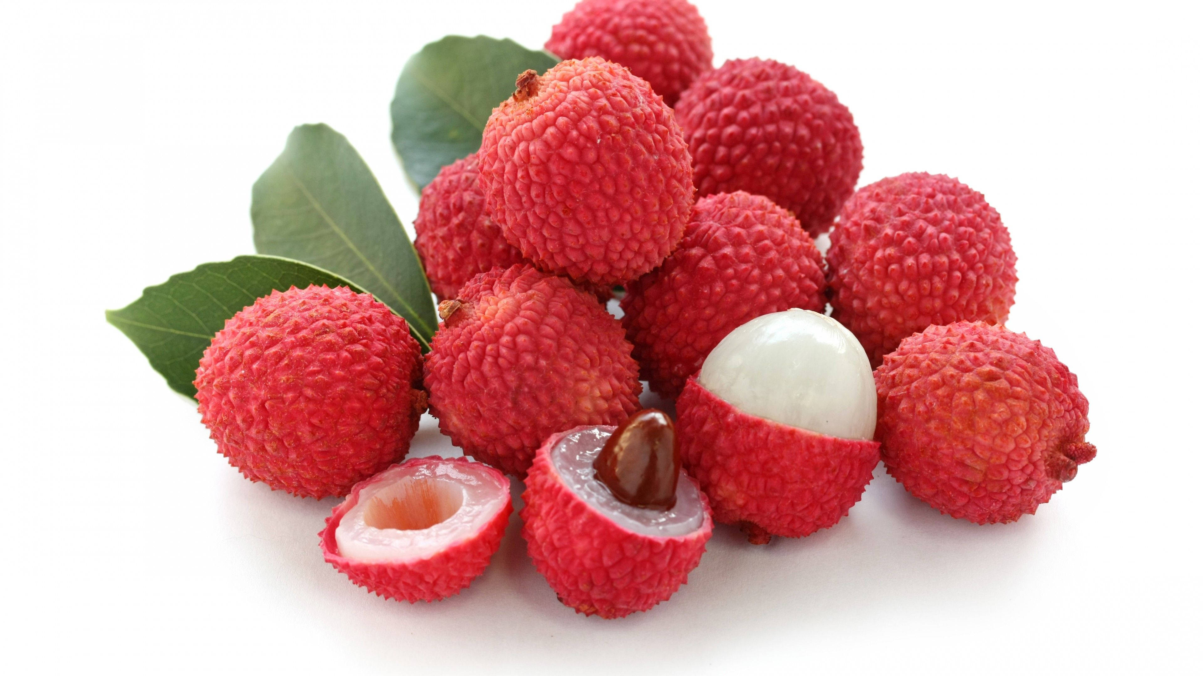 Fruits 桌布 壁紙 — 新鮮紅荔枝，外皮凹凸不平，果肉晶瑩剔透，旁邊有綠葉，置於潔白背景上。