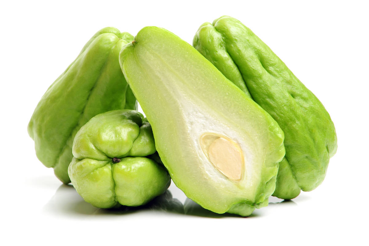 vegan 桌布 壁紙 — 新鮮綠色佛手瓜，其中一個切開，露出淡色內部及種子，背景為白色。
