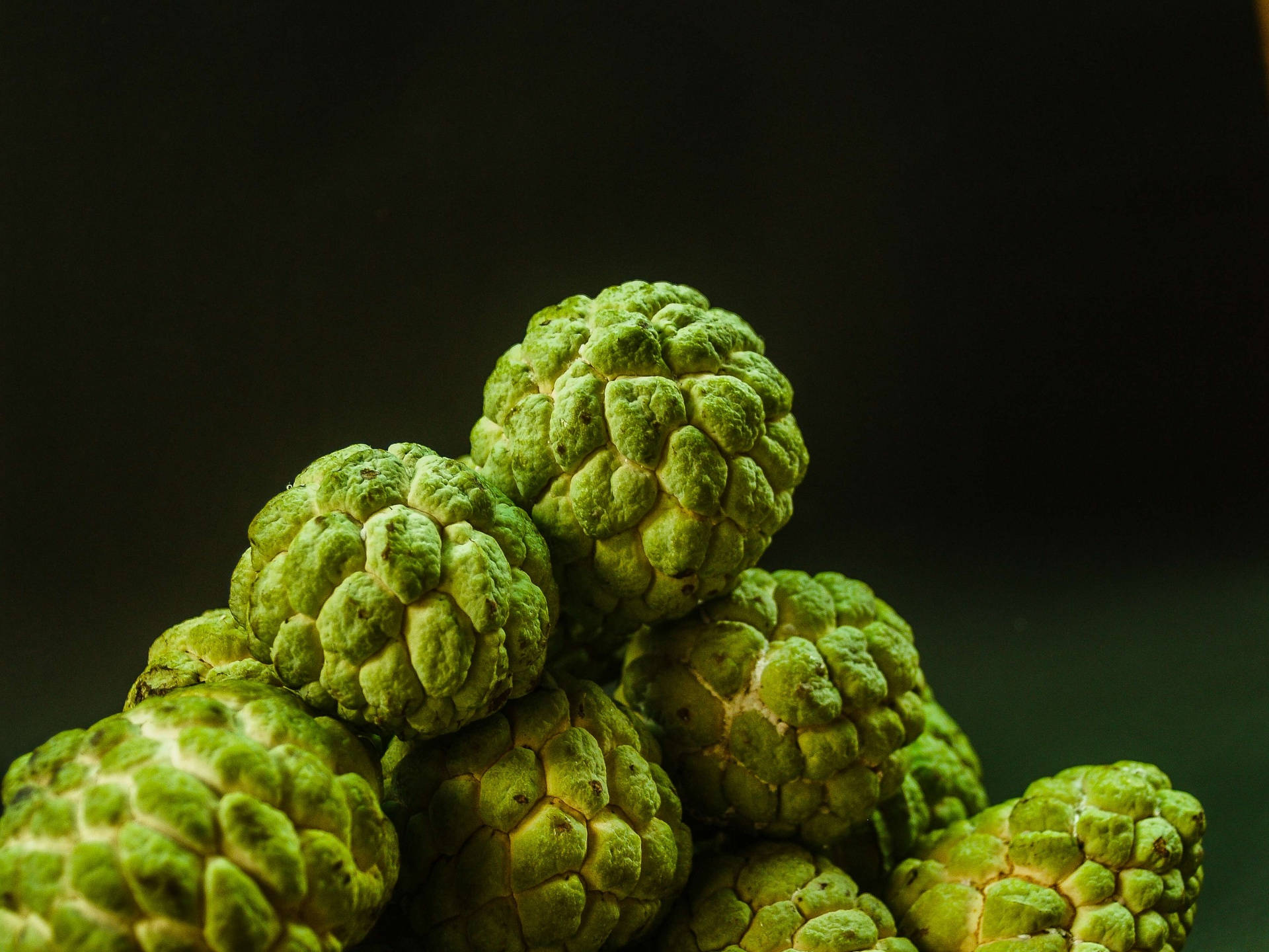 Fruit 桌布 壁紙 — 新鮮綠色刺果番荔枝堆疊在一起的近距離特寫，背景為深色。