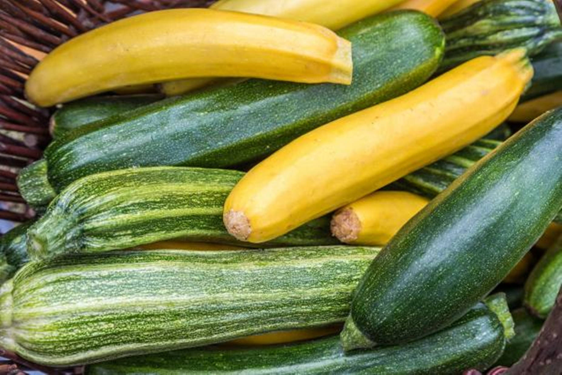 Vegetables 桌布 壁紙 — 新鮮綠色和黃色櫛瓜的特寫，堆放在編織籃中，帶有紋理表皮和天然莖部。