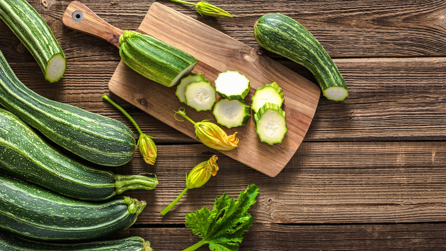 Healthy Food 桌布 壁紙 — 新鮮綠色櫛瓜搭配黃色花朵及切片圓塊，擺放在質樸木砧板上。