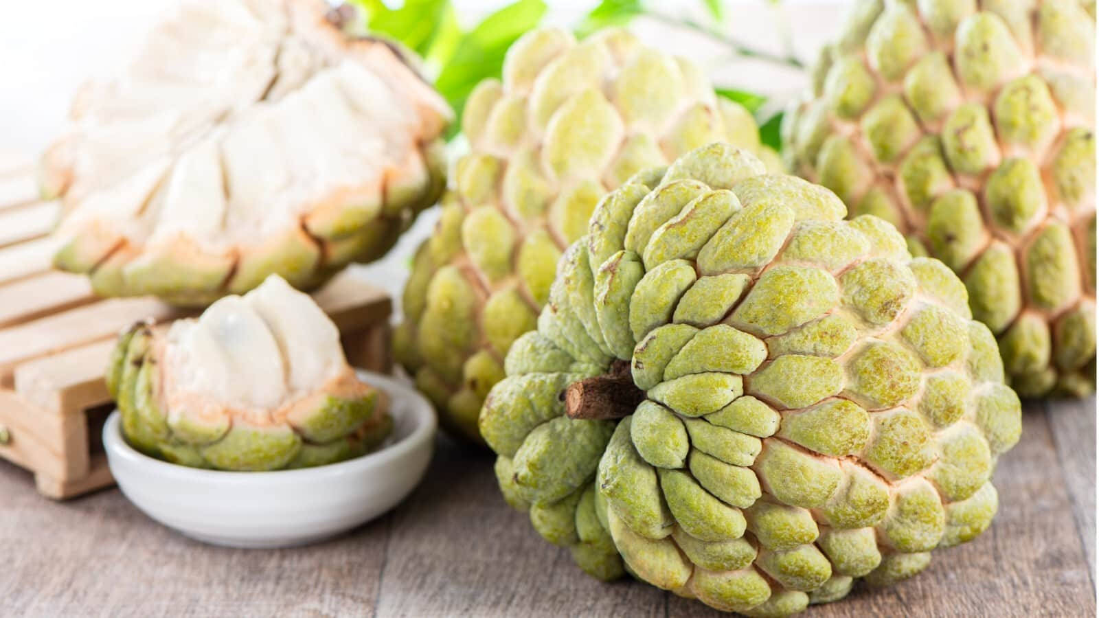 Fruit 桌布 壁紙 — 新鮮綠色牛油果（釋迦）帶有紋理外皮和奶油白色果肉，展示在質樸木質表面上。