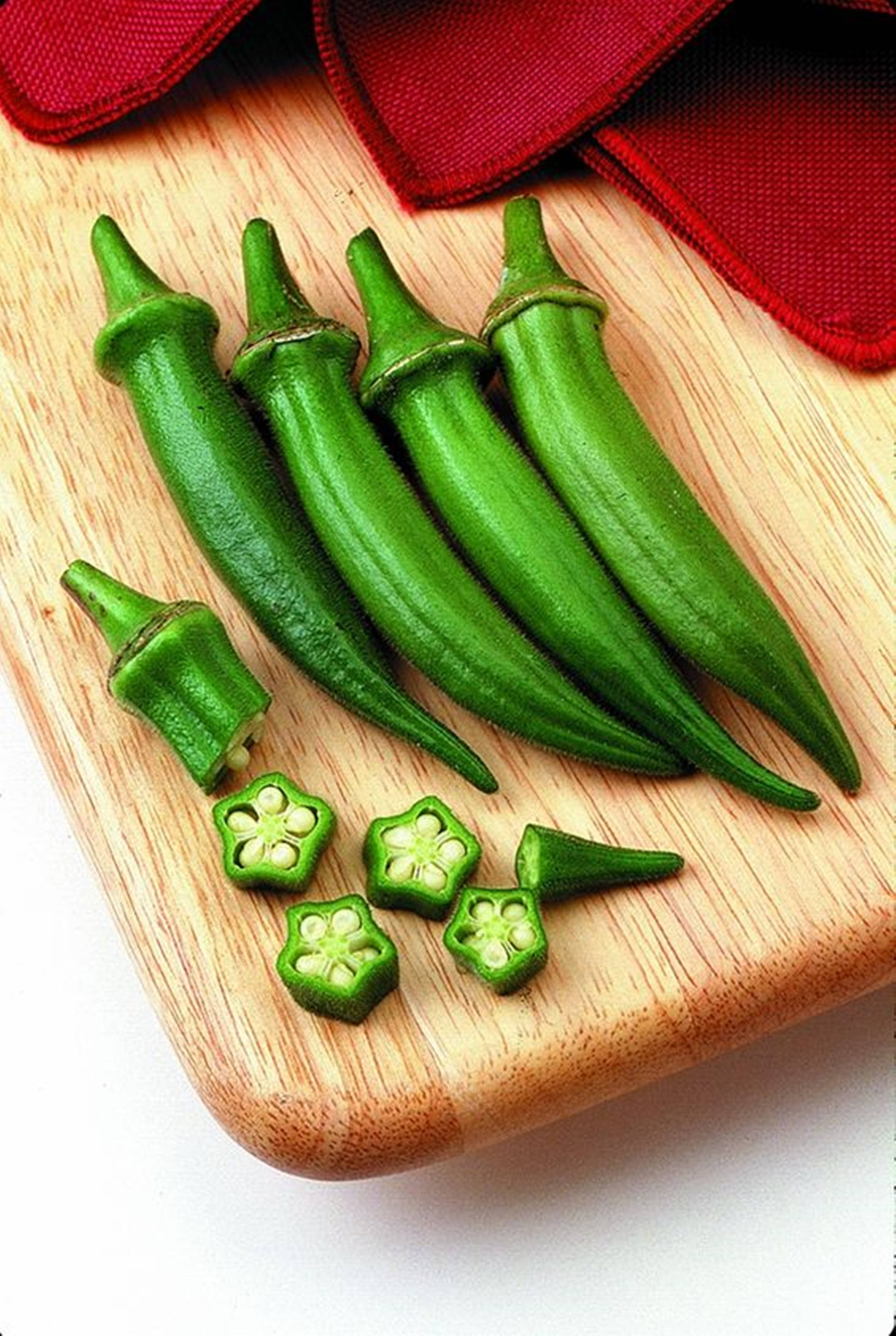 Healthy Food 桌布 壁紙 — 新鮮綠色秋葵莢和切片秋葵露出星形內部，放在木砧板上，旁邊有一塊紅布。