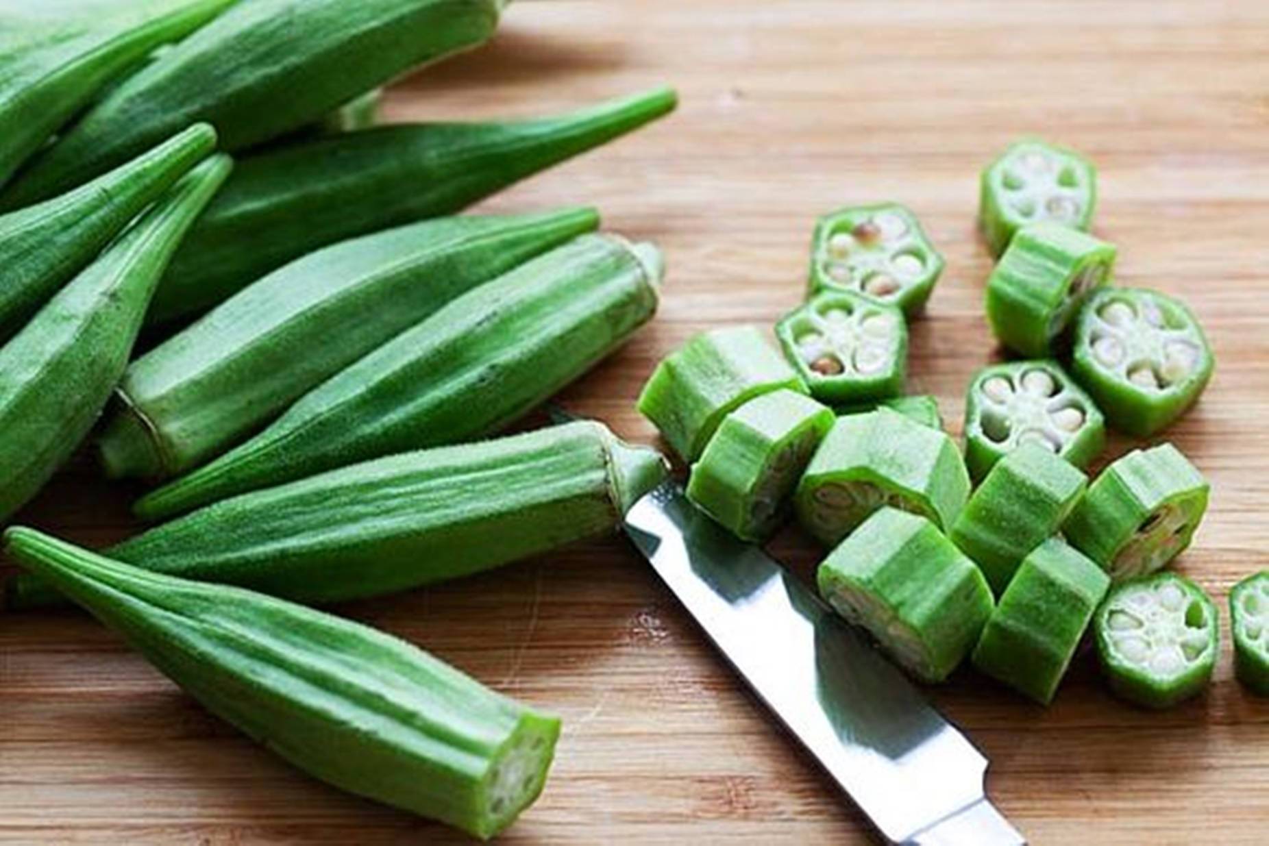 Healthy Food 桌布 壁紙 — 新鮮綠色秋葵莢完整及切片放在木砧板上，旁邊有刀。
