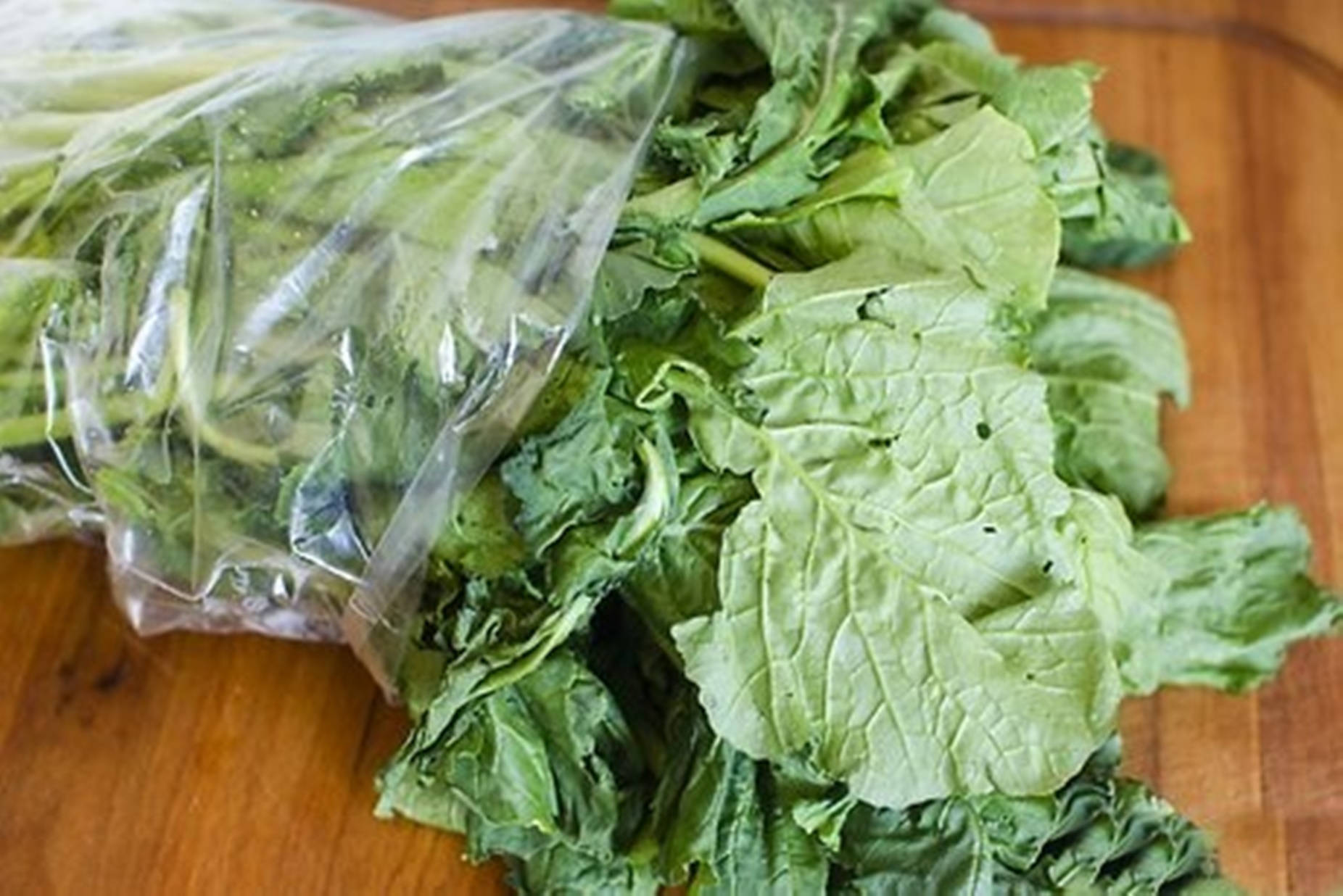 Vegetables 桌布 壁紙 — 新鮮綠色葉菜從透明塑膠袋灑落到溫暖的木砧板上。