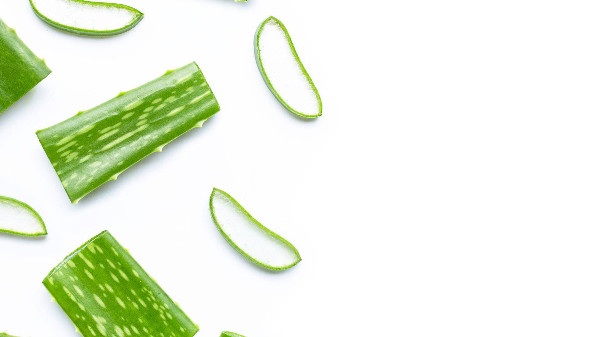 sliced 桌布 壁紙 — 新鮮綠色蘆薈切片排列在潔白背景上，展示其充滿凝膠的內部。