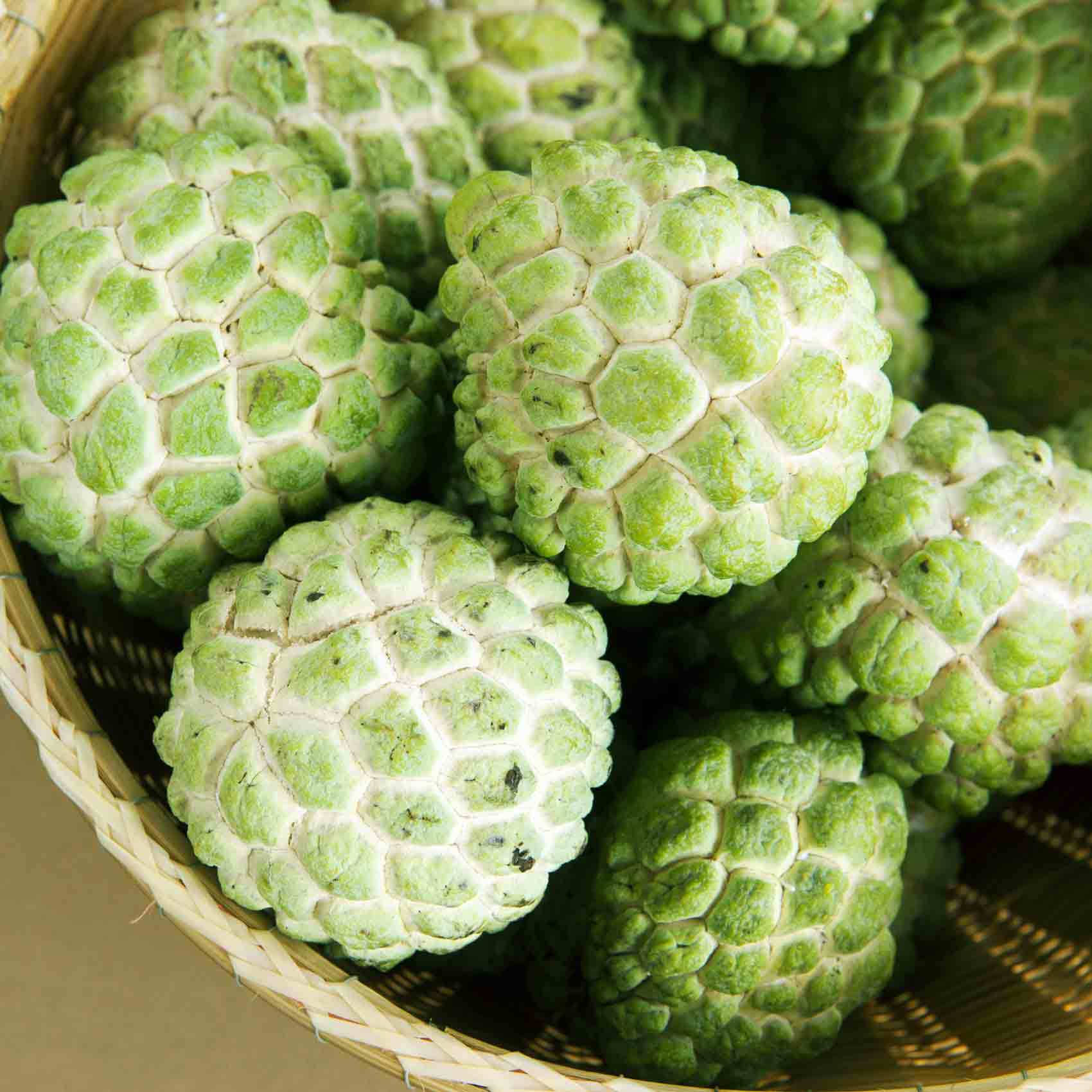 Fruit 桌布 壁紙 — 新鮮綠色釋迦果，帶有六角形紋理表皮，堆疊在編織竹籃中。