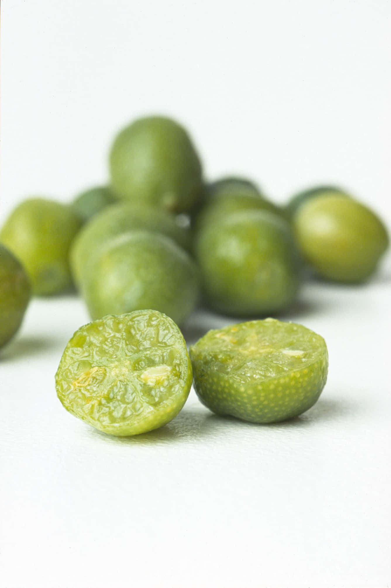 Lime 桌布 壁紙 — 新鮮綠色金桔切開，露出多汁果肉，襯以潔白背景。
