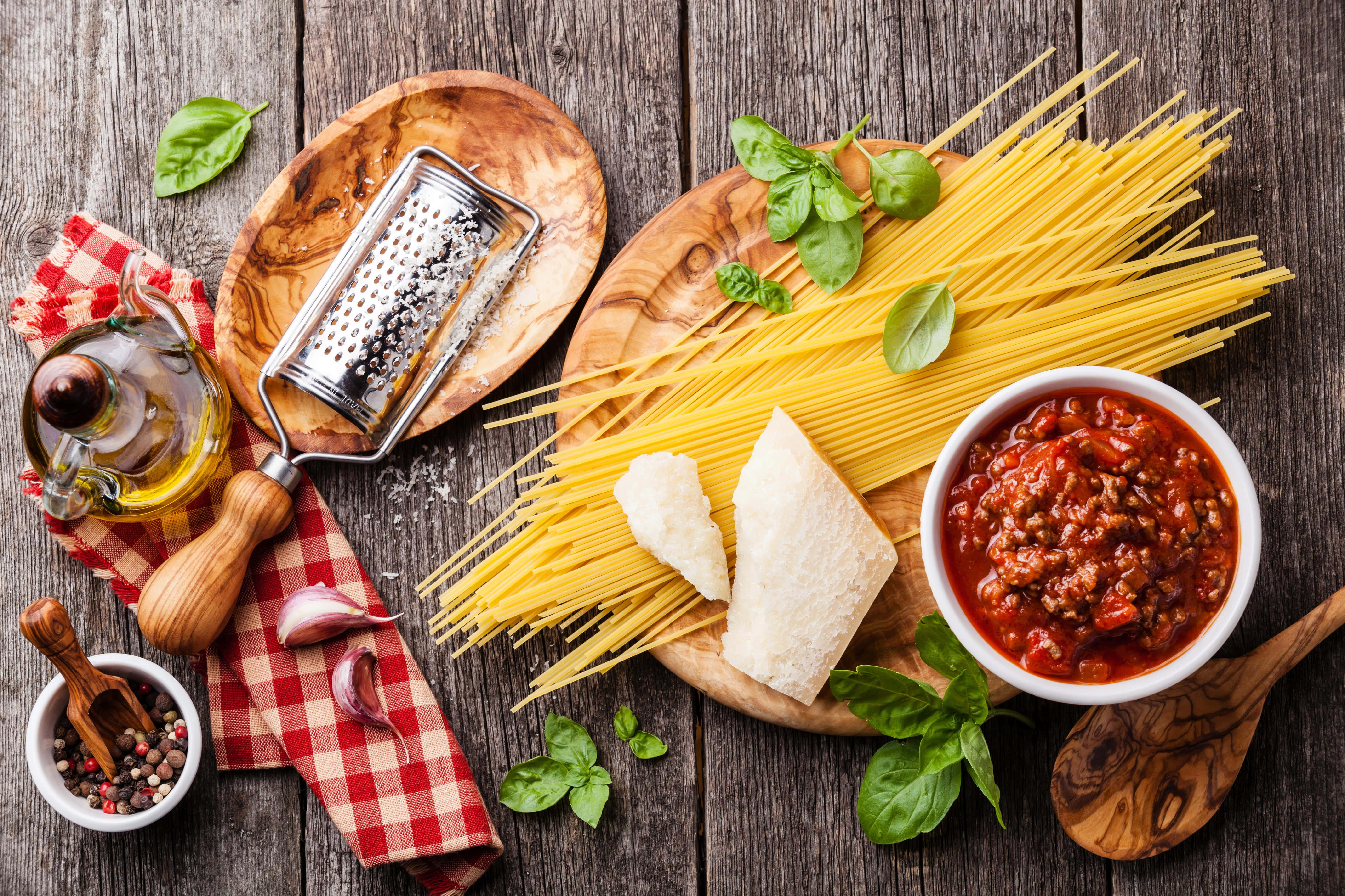 Pasta 桌布 壁紙 — 新鮮義大利麵、羅勒油、起司和醬汁擺放在鄉村風木板上，用於義大利烹飪。