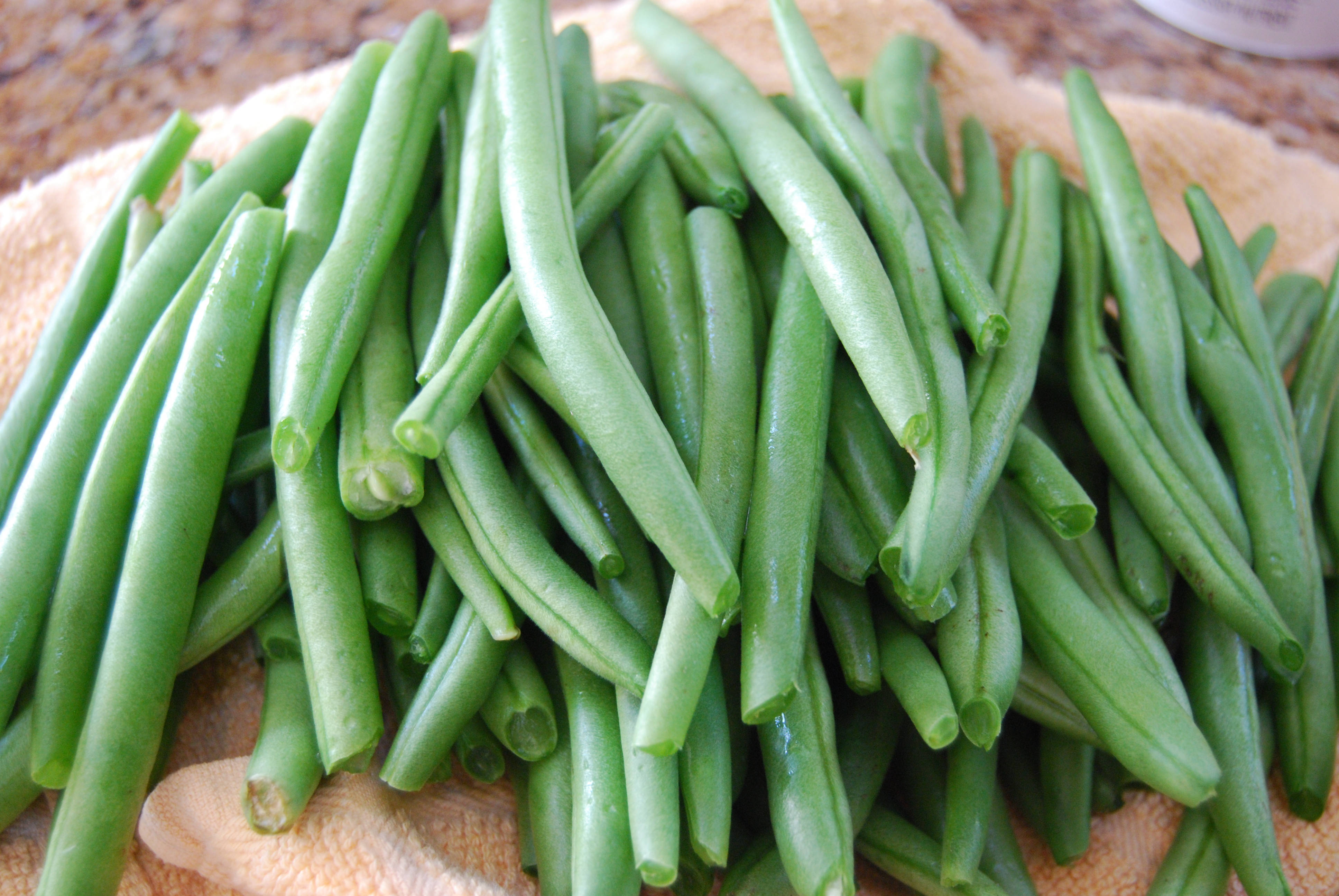 beans 桌布 壁紙 — 新鮮翠綠的四季豆高高堆在帶有紋理的米色毛巾上，帶有露珠般的光澤和自然光。