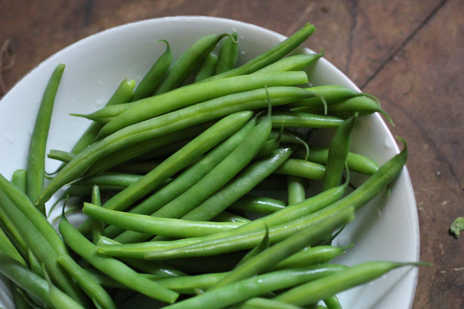beans 桌布 壁紙 — 新鮮翠綠的豆子在白色碗中閃閃發光，碗放在質樸的木質表面上。
